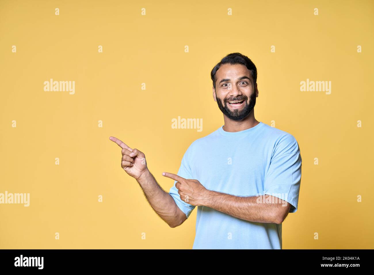 Aufgeregt indischen Mann zeigt Werbung kommerziellen Angebot isoliert auf gelb. Stockfoto