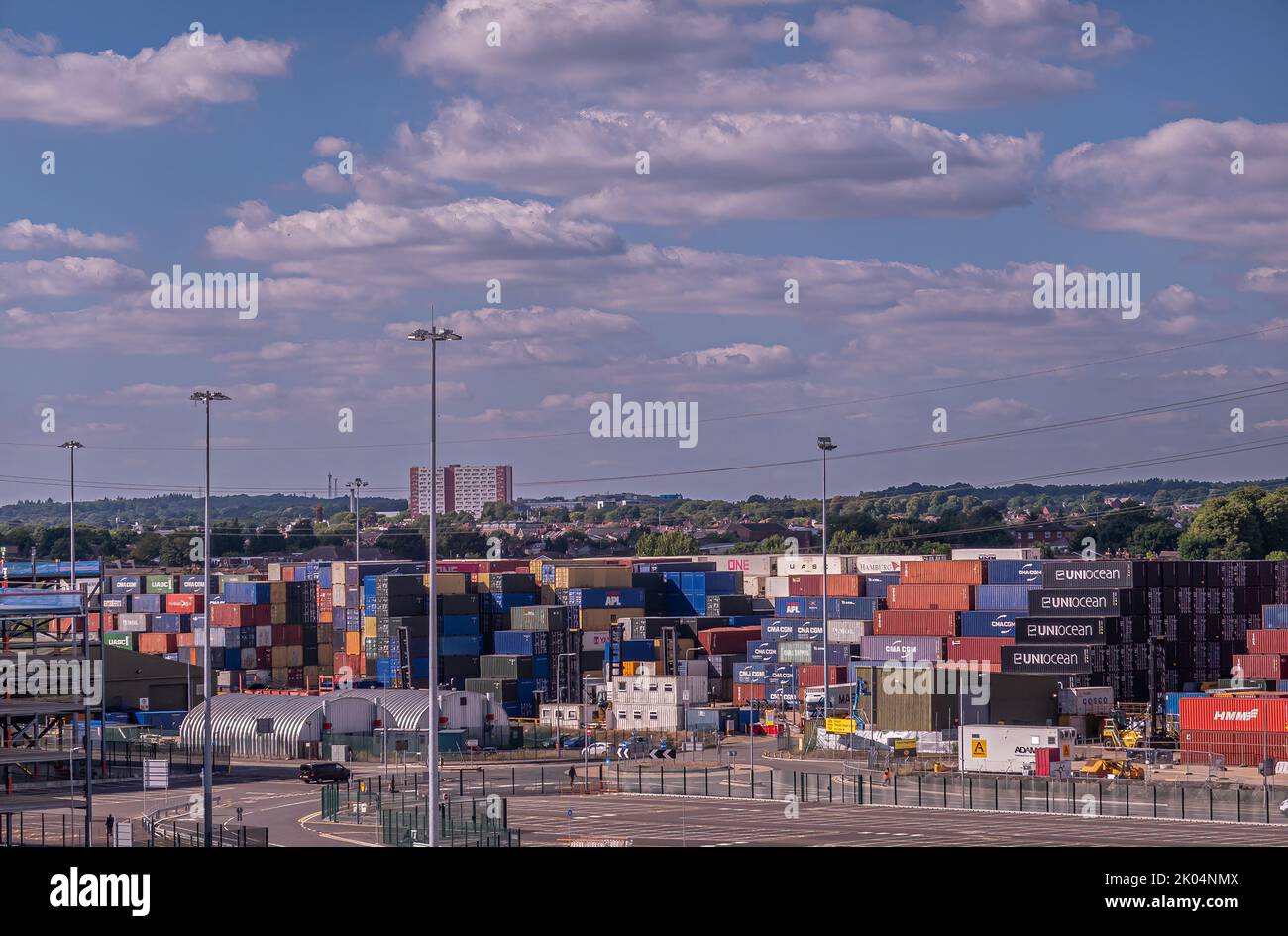 Southampton, England, Großbritannien - 7. Juli 2022: Hafenlandschaft. Lange Stapel farbiger Transportbehälter am Dock im Hafen. Stadtbild im Rücken, Grüngürtel und Stockfoto