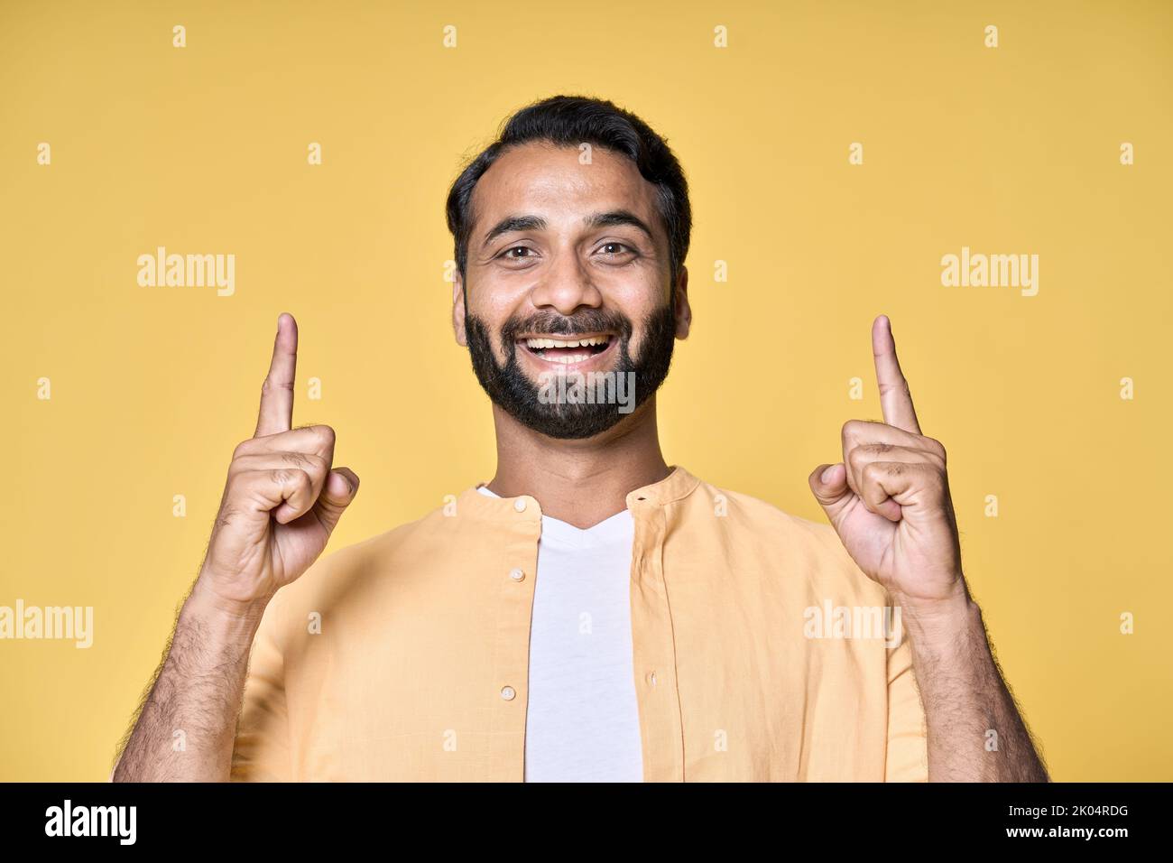 Lächelnder indischer Mann zeigt Finger nach oben Werbung isoliert auf gelbem Hintergrund. Stockfoto