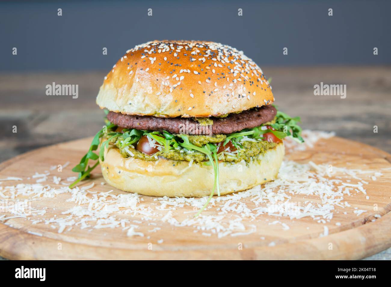 Veganer Hamburger ohne Fleischalternative. Burger auf pflanzlicher Basis mit Pesto, veganem Käse und Bio-Kirschtomaten. Street Fast Food. Hausgemachtes Brötchen. Stockfoto