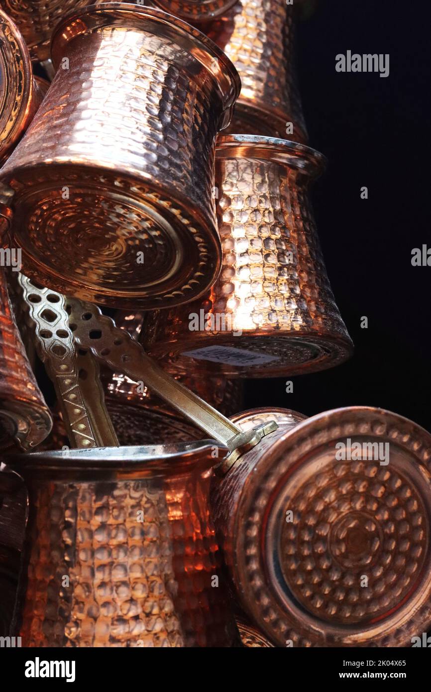 Ein Haufen türkisch geprägter cooper-Bronze-Kaffeekannen hängt auf dem orientalischen Marktplatz in Heildeberg. Schließenbild, Seitenansicht. Schwarzer Hintergrund. Spa Kopieren Stockfoto