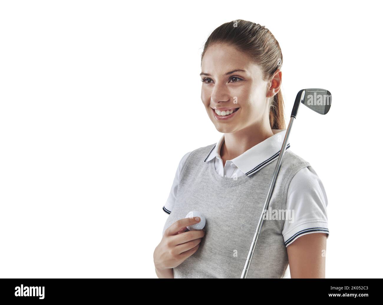 Shes hat den Willen zu gewinnen. Studioaufnahme eines jungen Golfers, der einen Golfball und einen Eisenklub in Weiß hält. Stockfoto