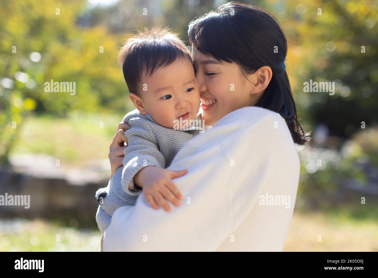 Junge chinesische Mutter spielt mit Baby im Park Stockfoto