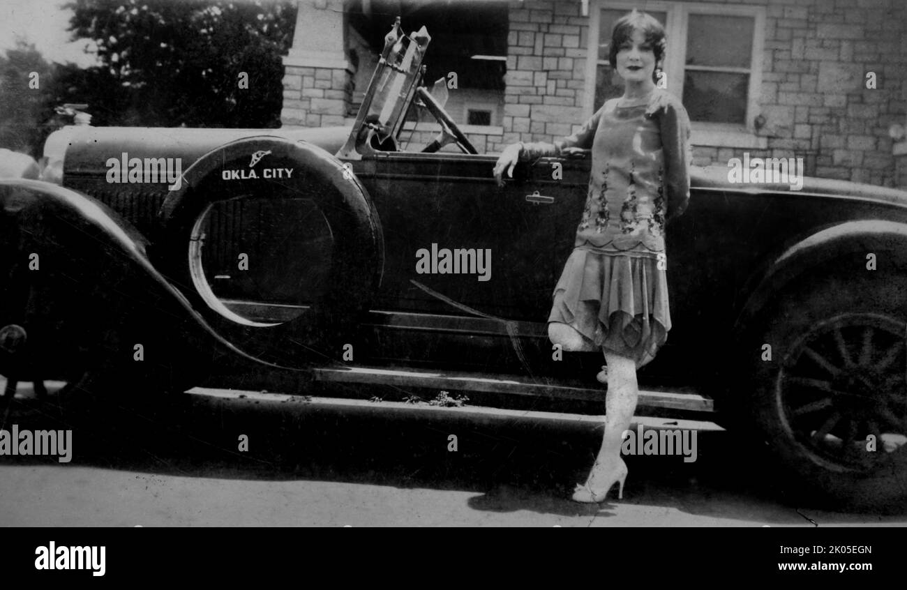 Eine junge Frau steht neben einem historischen Automobil, Ca. 1920er. Stockfoto Eine junge Frau steht neben einem historischen Automobil, Ca. 1920er. Stockfoto