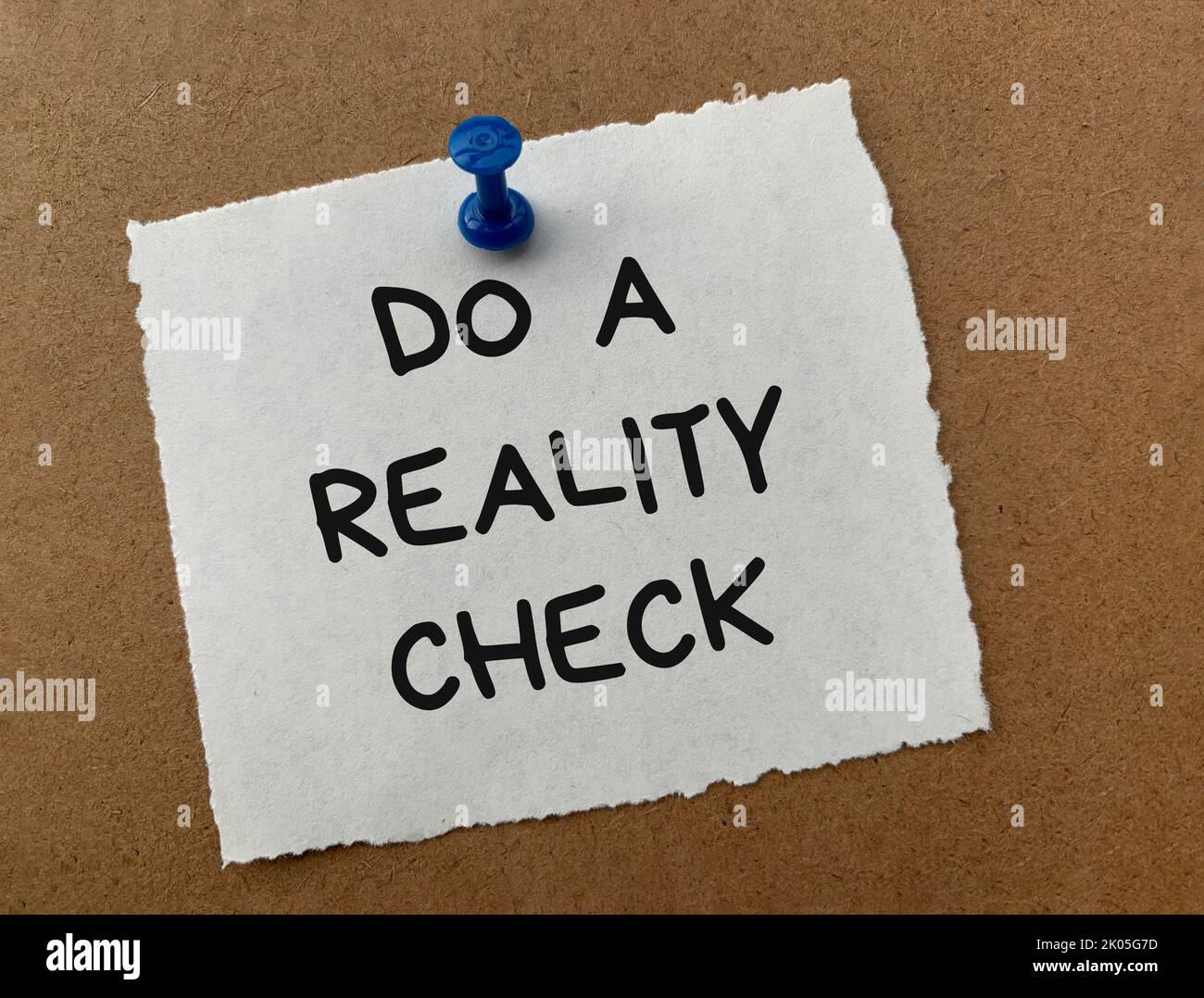 Führen Sie einen Reality-Check-Text auf weißem Notizblock mit Holzhintergrund durch. Reality-Check-Konzept. Stockfoto