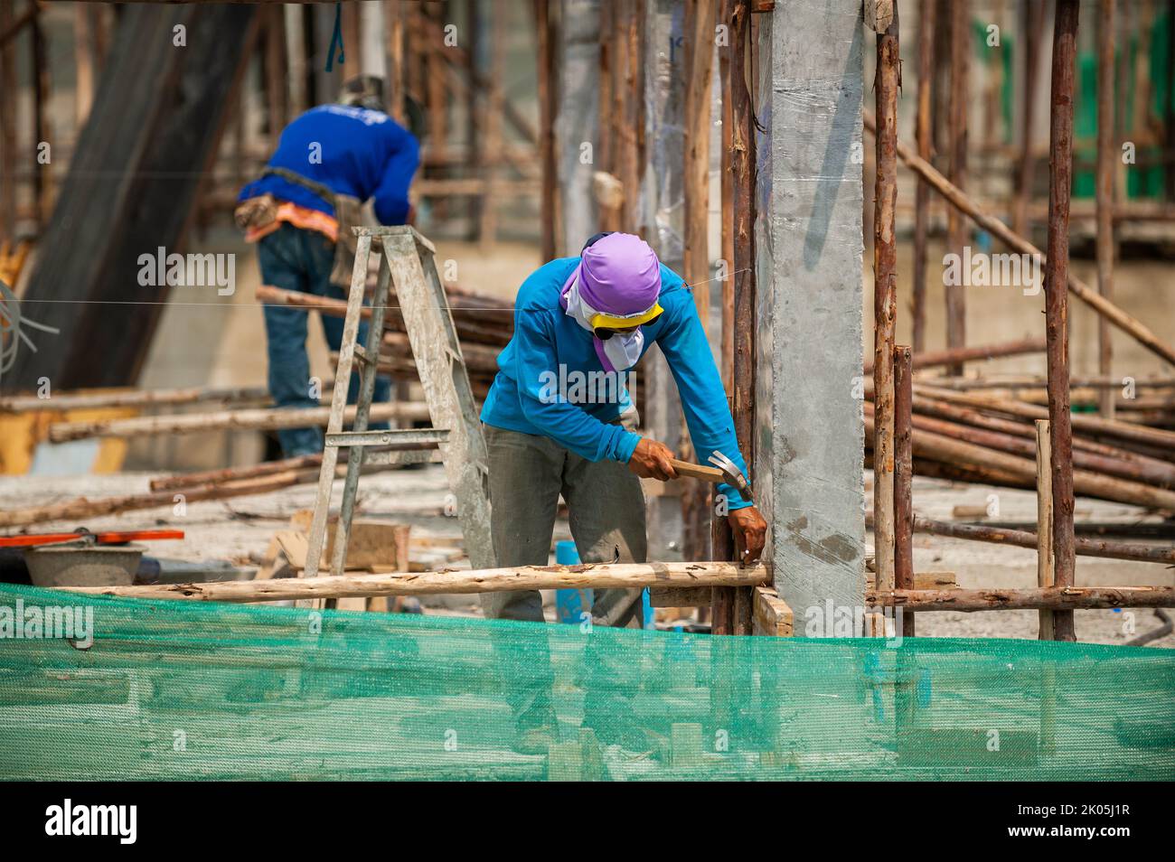Bangkok, Thailand 5. September 2015: Bauarbeiter nagelt temporäre Holzmasten als Streben an Betonsäulen Stockfoto