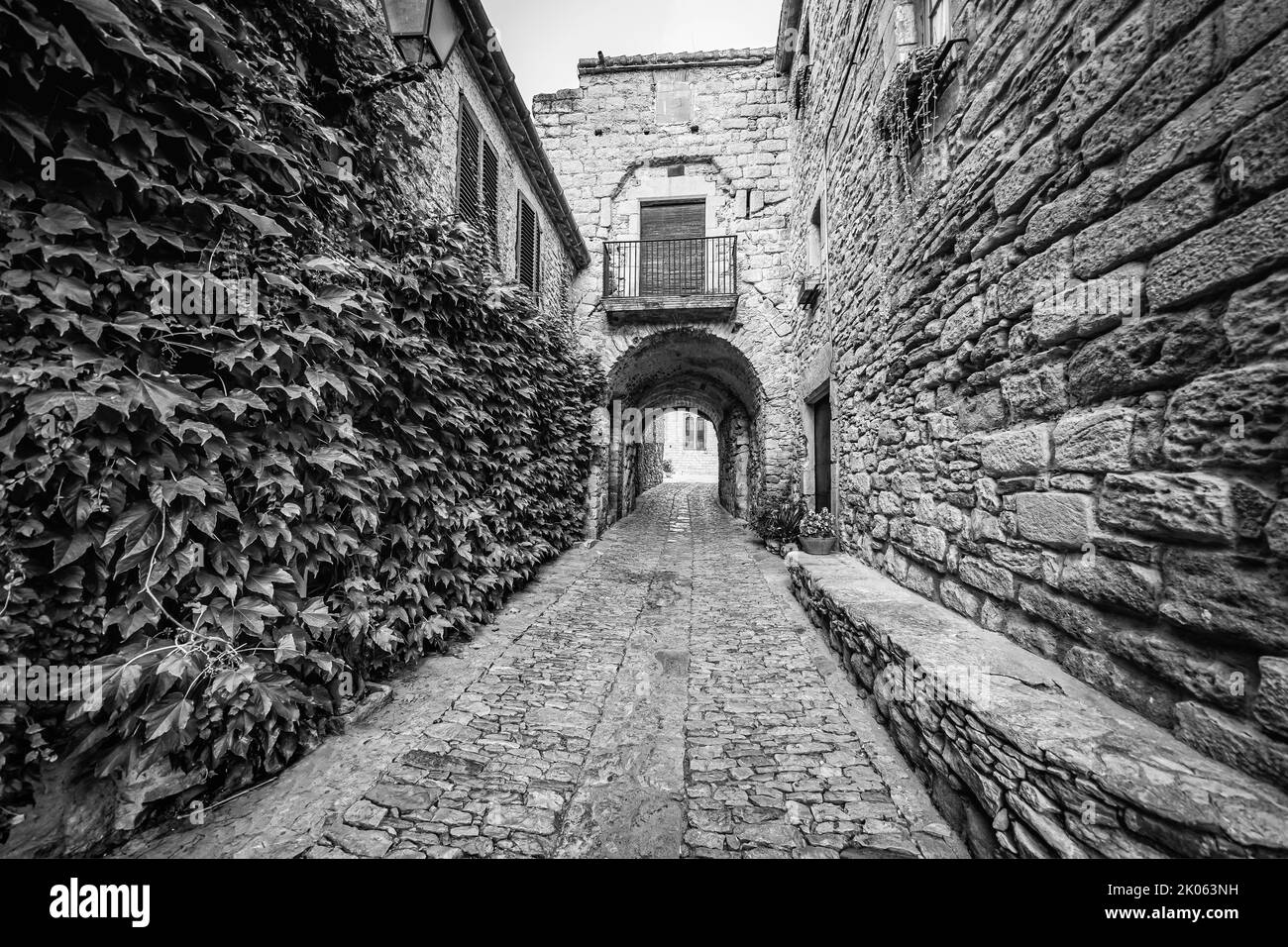 Gasse mit alten Steinhäusern und bogenförmigem Durchgang am Ende des Tunnels, Peratallada, Girona. Stockfoto