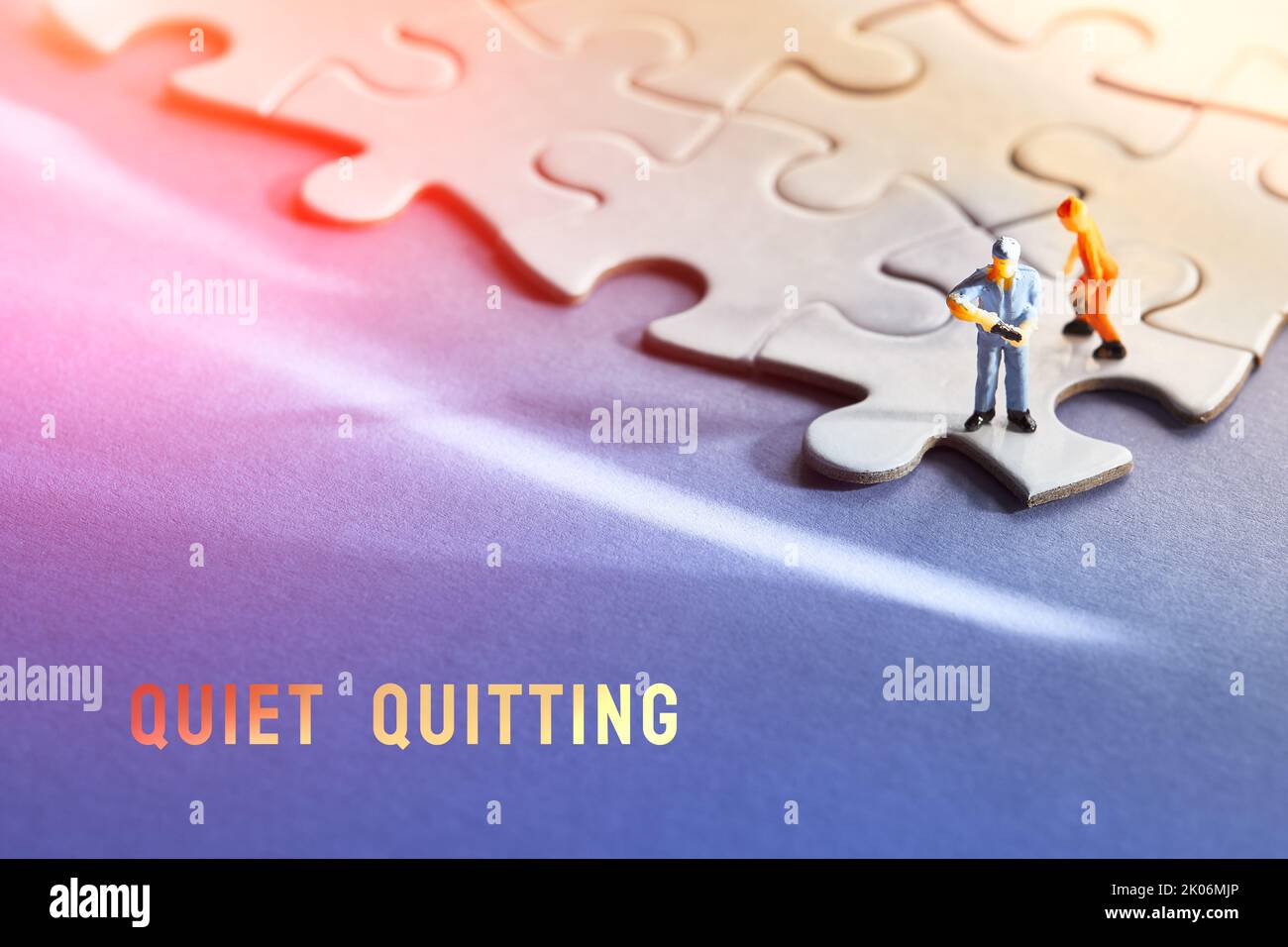 Einzelne kleine Arbeiter Miniatur-Figur am Rand des verbundenen Puzzle. Blau-violetter Hintergrund aus Papier mit Farbverlauf, langer Schatten, Lichtreflexe. Hintergrund des Konzepts. Stockfoto