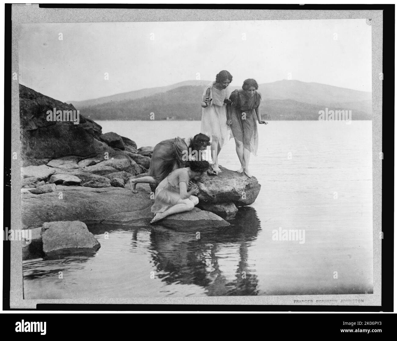 Vier Zahlen am Wasserrand, c1914. Vier Frauen in klassischer Drapiererei auf Felsen in der Nähe des Wassers. Stockfoto
