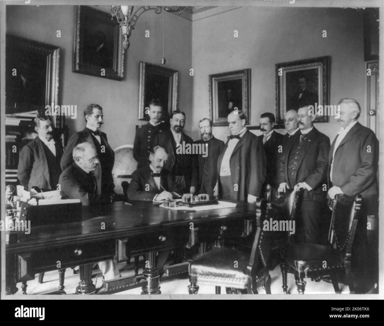Unterzeichnung des Friedensprotokolls - Washington - 12.. August 1898, c1898. Eugene Thiebaut(?) Unterschreiben, als William McKinley und zehn andere Männer sich angucken. Stockfoto