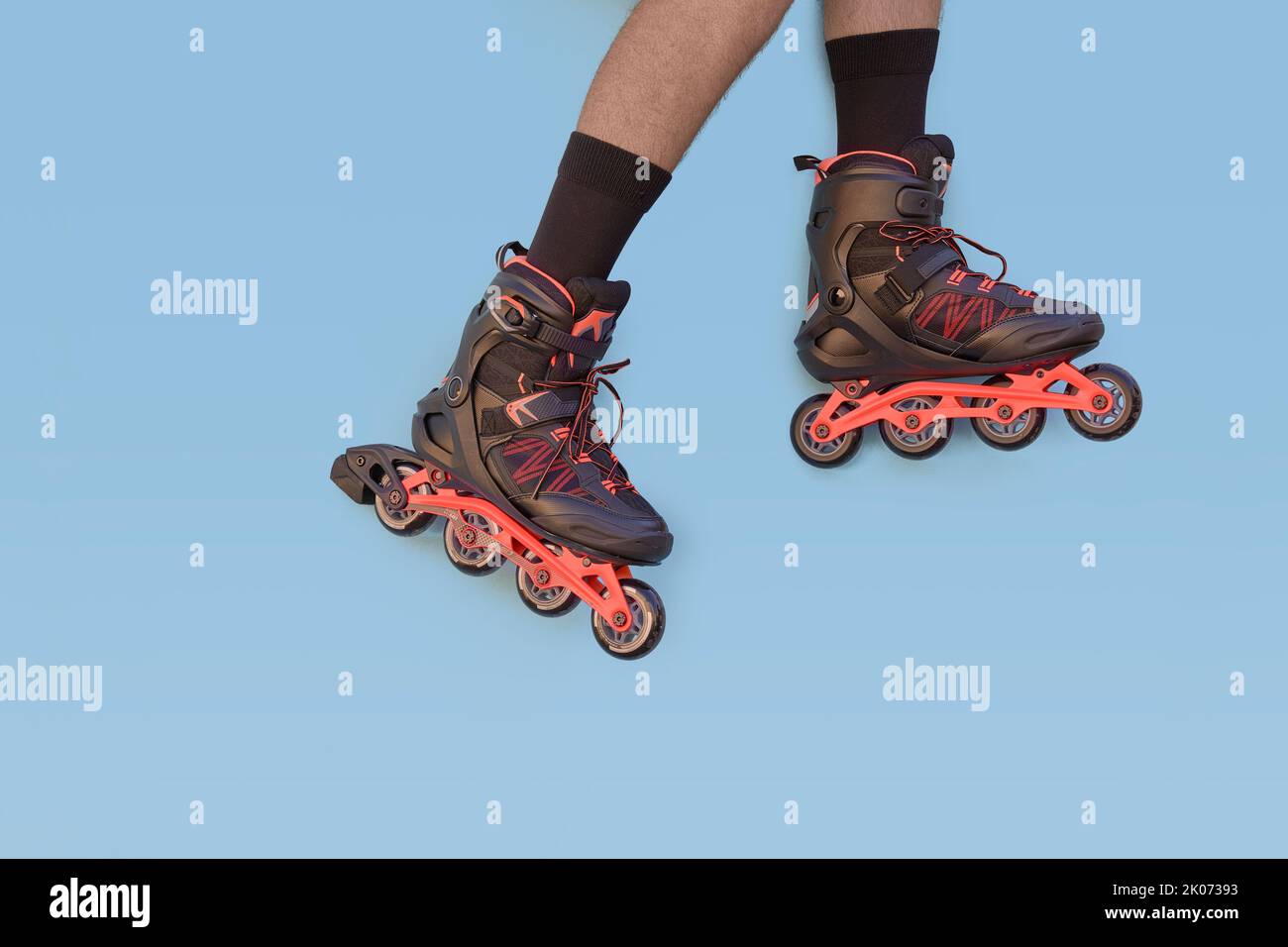 Zwei Beine eines Jungen mit Inline-Skates auf blauem Hintergrund mit Copyspace Stockfoto