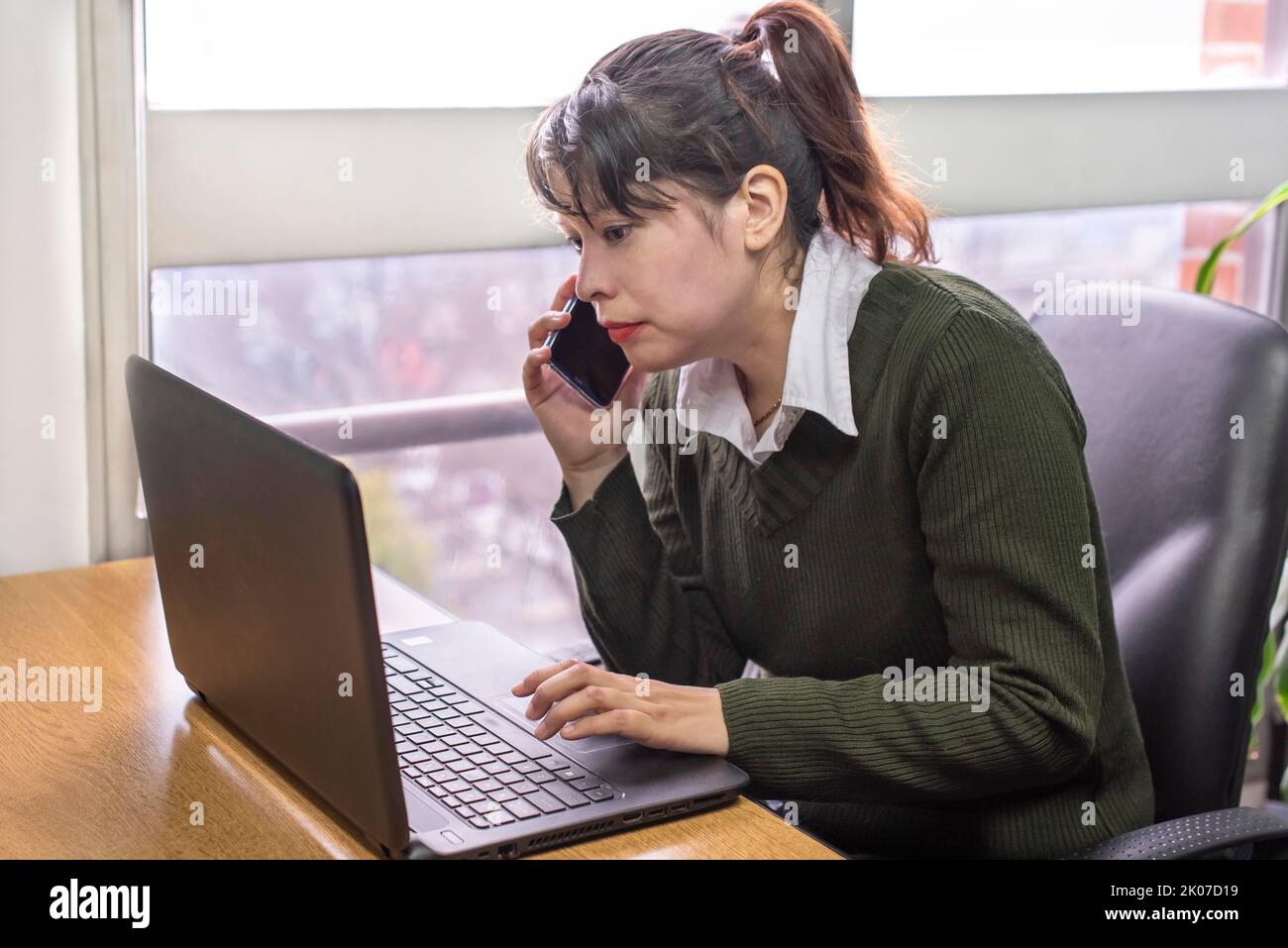 Porträt einer Frau, die im Büro an ihrem Laptop arbeitet Stockfoto