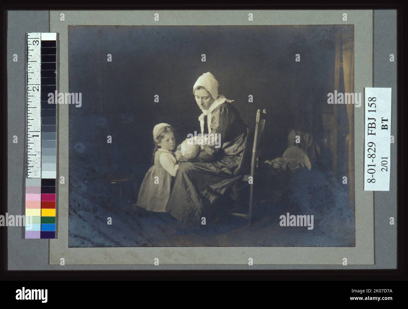 Das Baby, 1901. Das Foto zeigt eine Frau und ein kleines Mädchen, beide in "holländischer" Kleidung gekleidet, und sieht ein Kleinkind in den Armen der Frau. Stockfoto