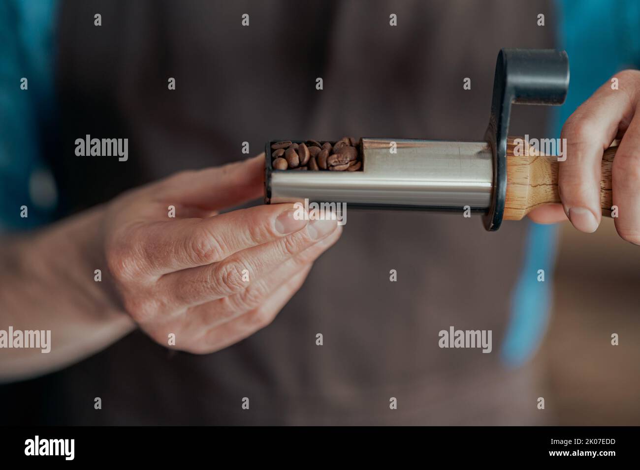 Die Hände des Mannes halten frisch geröstete aromatische Kaffeebohnen, die in kleiner Produktion stehen Stockfoto