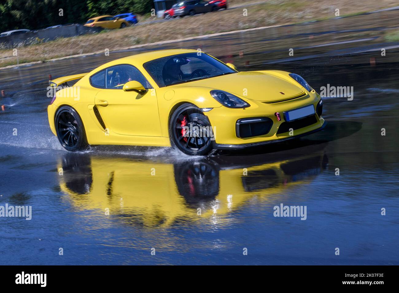 Sportwagen-Rennwagen Porsche Cayman GT4 auf künstlich regennasser Fahrbahn während des Fahrsicherheitstrainings Kufen durch Aquaplaning, im Vordergrund Stockfoto