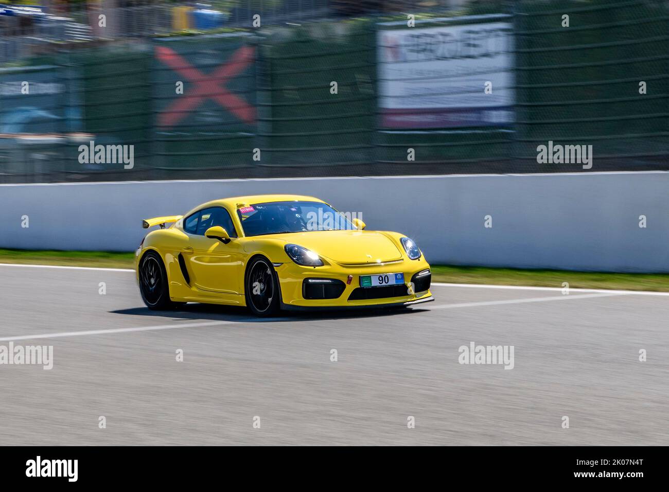 Gelber Rennwagen-Sportwagen Porsche Cayman GT4 fährt während des Trackday mit Höchstgeschwindigkeit auf der Start-Ziel-Geraden der Rennstrecke FIA Formula 1 Stockfoto