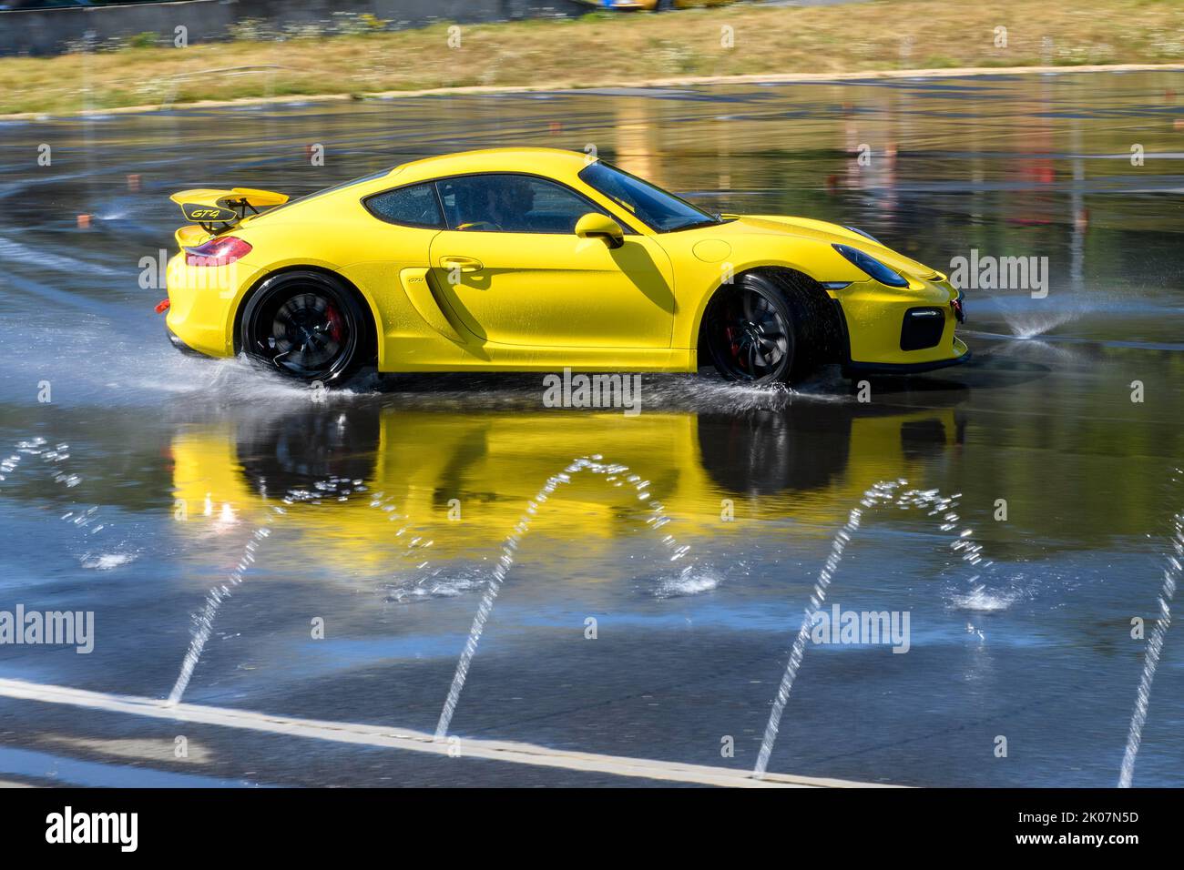 Sportwagen-Rennwagen Porsche Cayman GT4 auf Regenbahn Driften Driften über nassen Asphalt während des Fahrsicherheitstrainings, im Vordergrund Wasser Stockfoto