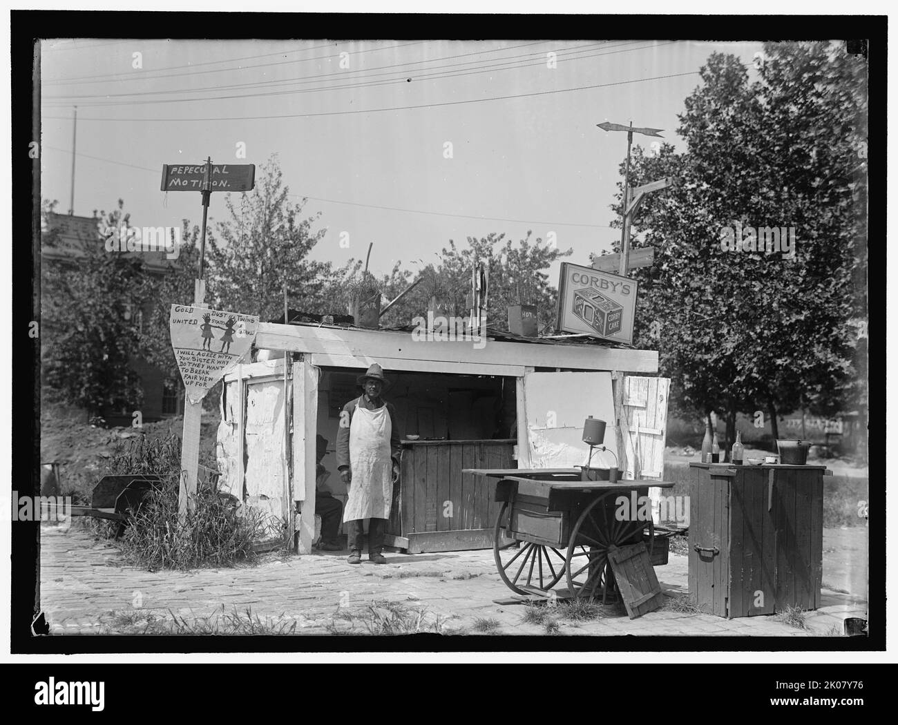 Fairview Hotel, zwischen 1910 und 1917. Mann im Vorfeld an einem Lebensmittelstand am Straßenrand, USA? Zeichen: 'Pepecual [sic] Bewegung; Gold Dust Twins United Wir stehen; Ich stimme mit Ihrer Schwester überein, warum sie Fairview für Corby's Cake brechen wollen'. Stockfoto