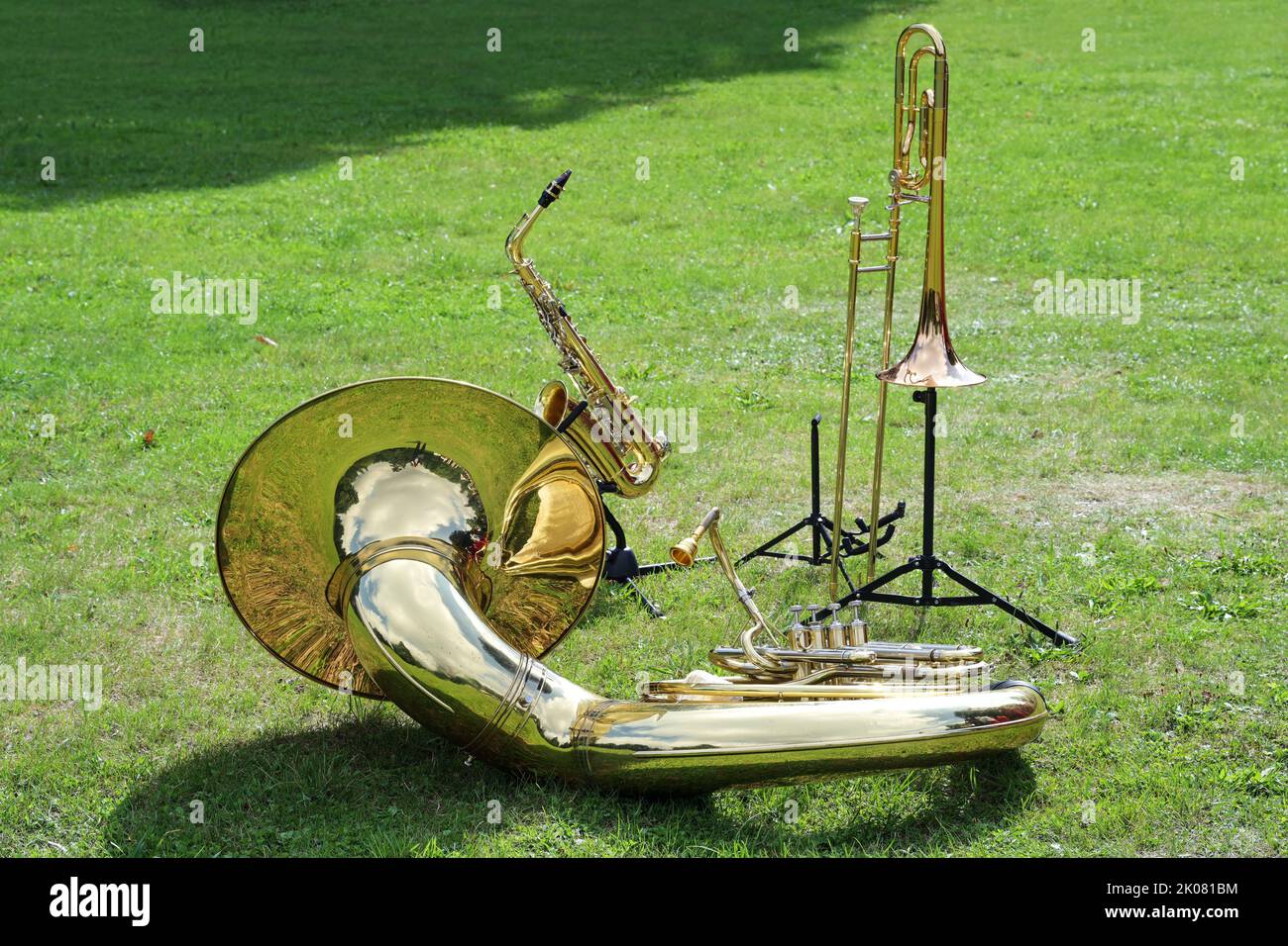 Verschiedene Musikblasinstrumente wie Sousaphon, Posaune und Saxophon, die auf dem Rasen im Park platziert wurden und darauf warten, in der Musikband Cop eingesetzt zu werden Stockfoto