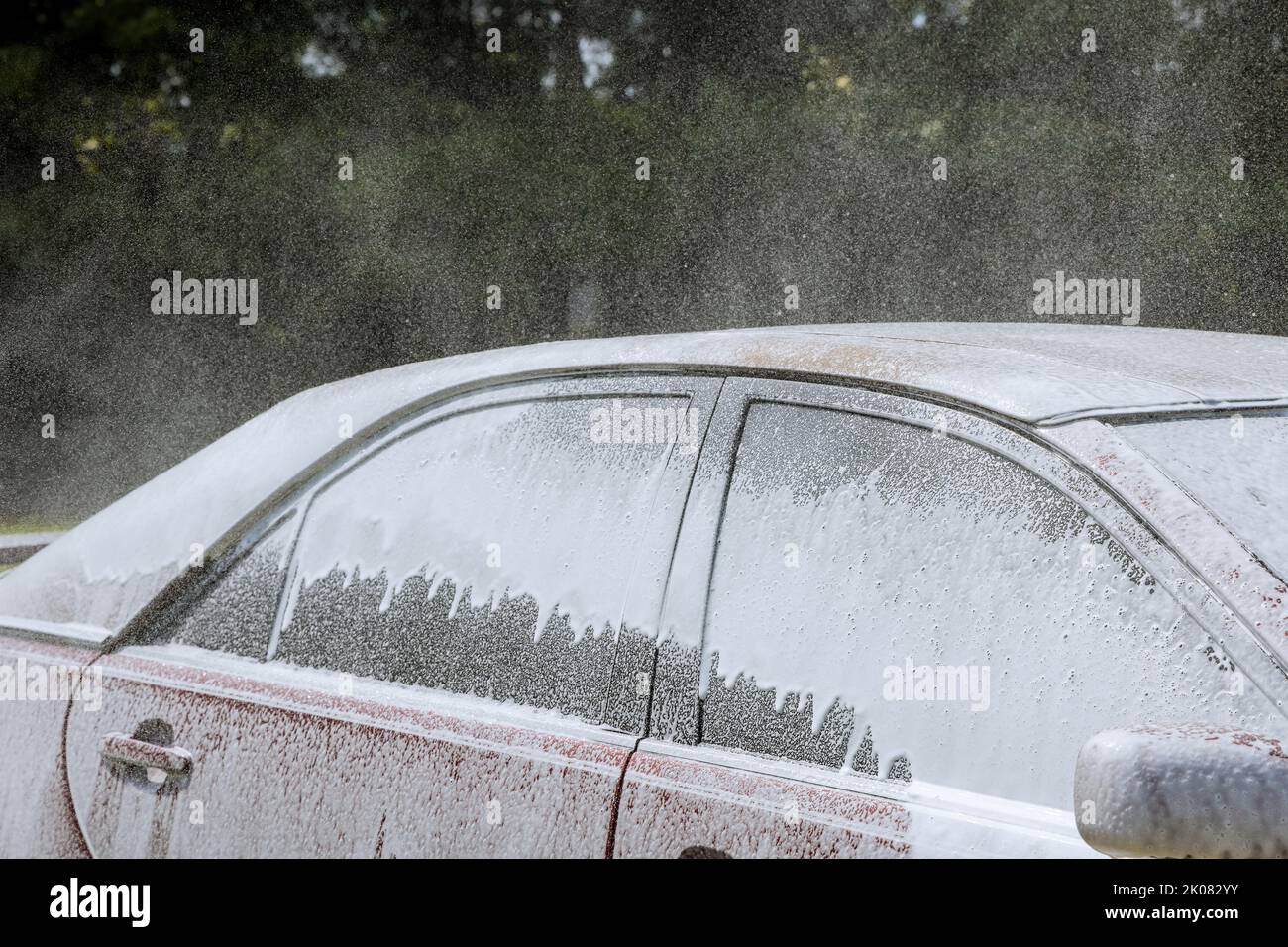 Während des Waschprozesses eines Autos in einer Autowäsche wird ein Power-Wasserstrahl verwendet, um Seifenwasserlösung zu sprühen Stockfoto