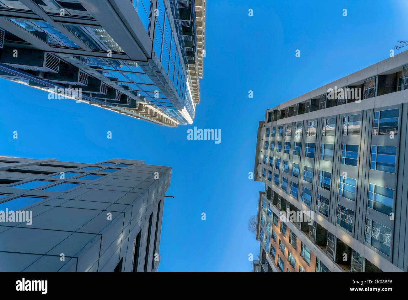 Moderne Apartments mit sonnendurchfluteten Außenflächen vor dem strahlend blauen Himmel an einem sonnigen Tag. Blick auf moderne Wohngebäude mit Fenstern, die das widerspiegeln Stockfoto