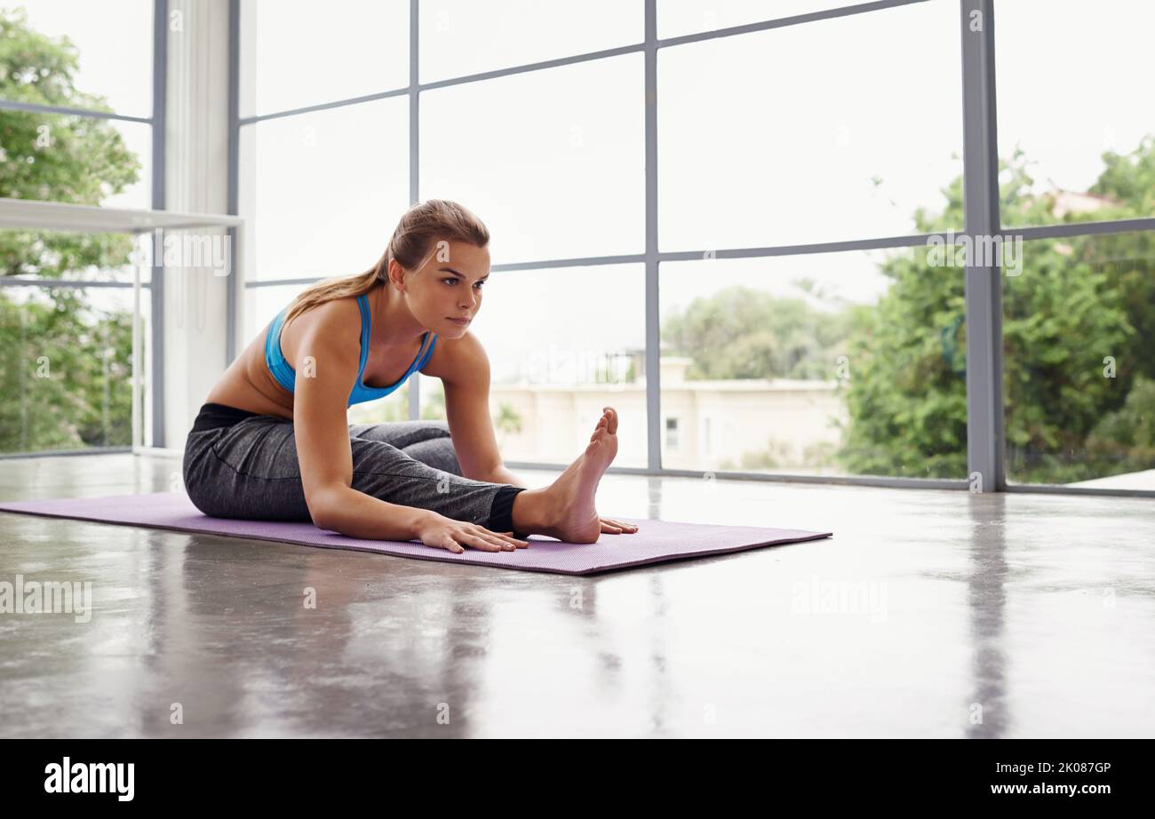 Entschlossen, fitter zu werden. Ganzkörperaufnahme einer sportlichen Frau, die zu Hause Yoga praktiziert. Stockfoto
