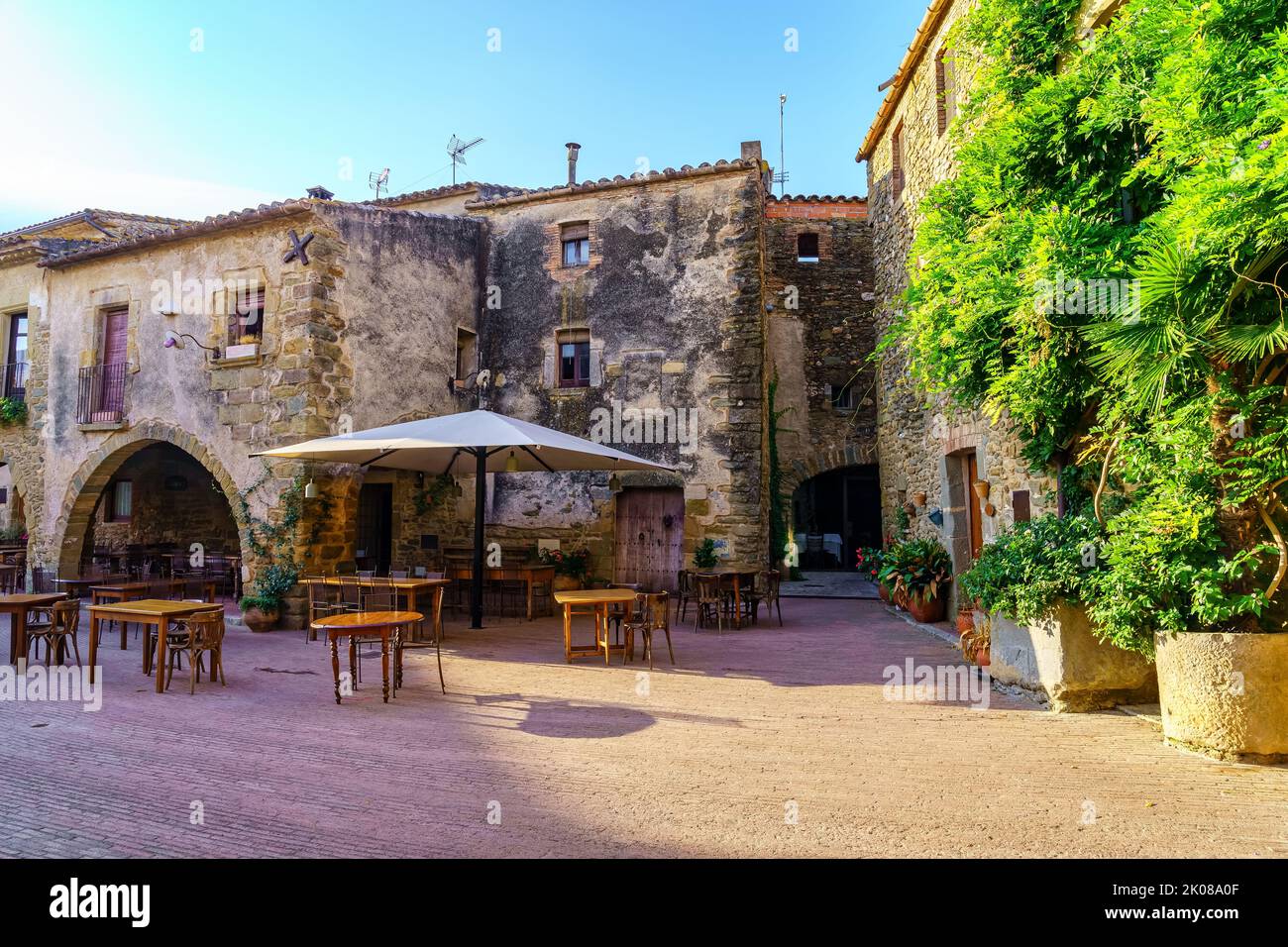 Zentraler Platz des schönen mittelalterlichen Dorfes Monells mit seinen Steinhäusern und grünen Reben, Girona Katalonien. Stockfoto