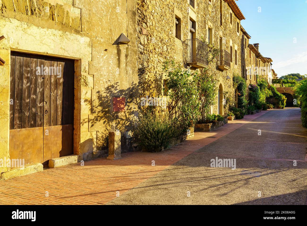 Traditionelle Steinhäuser mit grünen Blumentöpfen und Blumen im katalanischen Dorf Monells, Girona. Stockfoto