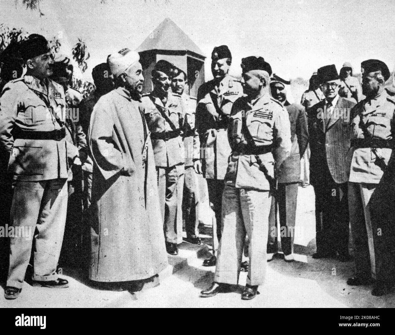 König Abdullah von Transjordan (links) mit Brigadier Glubb Pascha und Stabsoffizieren. Abdullah i bin al-Husain (2. Februar 1882 - 20. Juli 1951) war vom 11. April 1921 bis zu seiner Tötung im Jahr 1951 Herrscher über Jordanien. Er war bis zum 25. Mai 1946 Emir von Transjordan, einem britischen Protektorat, und danach König eines unabhängigen Jordans. Generalleutnant Sir John Bagot Glubb, KCB, CMG, DSO, OBE, MC, KStJ, KPM (16. April 1897 - 17. März 1986), bekannt als Glubb Pasha, war ein britischer Soldat, Gelehrter und Autor, der zwischen 1939 und 1956 Transjordan's Arab Legion als Kommandeur von ge leitete und trainierte Stockfoto