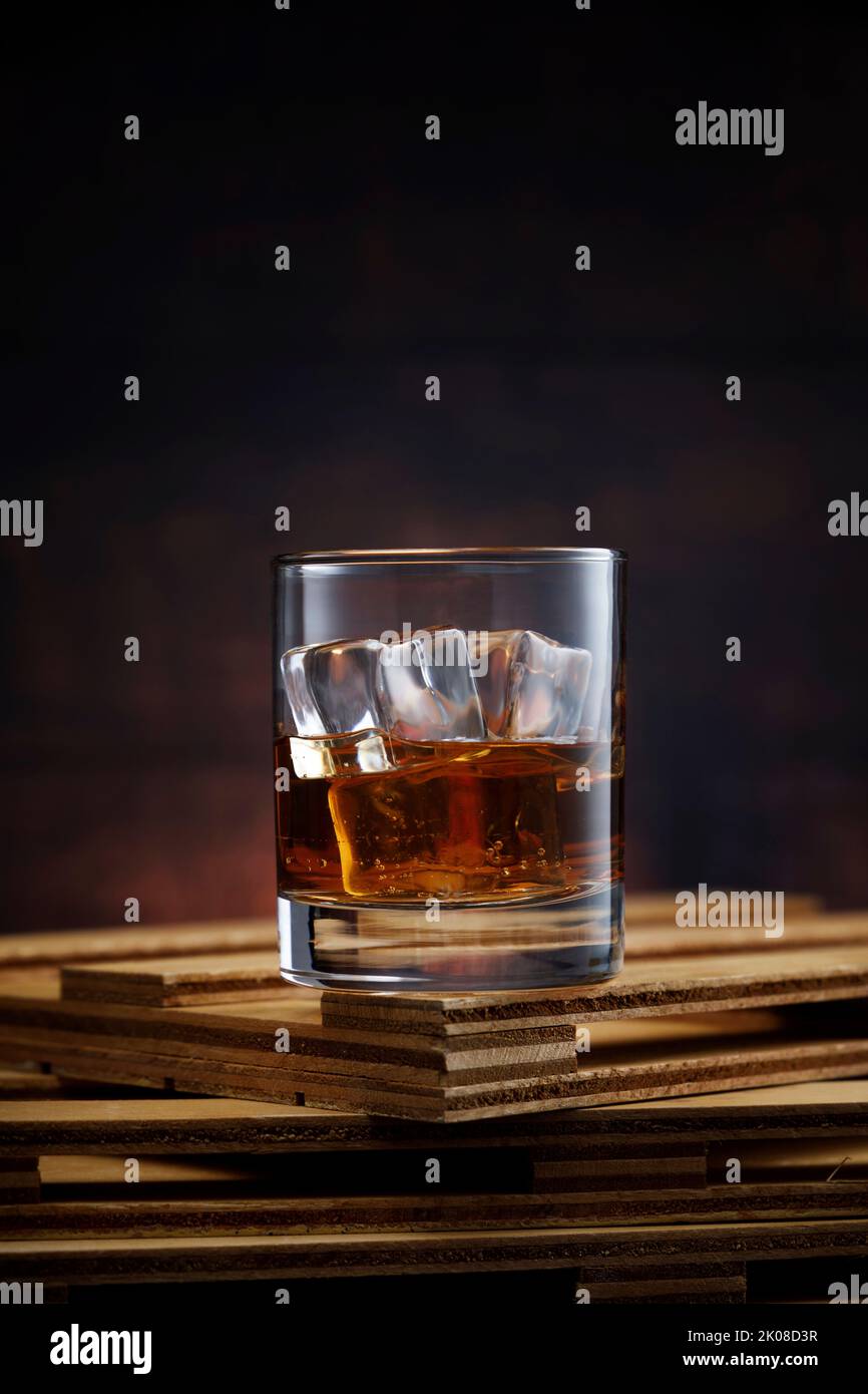 Kristallglas mit Whiskey und Eis auf Holztisch Stockfoto