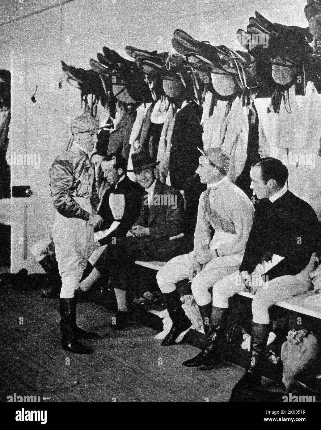 Jockey Archie Burns im Gespräch mit seinen Jockeys im Wiegeraum vor dem nächsten Rennen. Illustrierte Nachrichten schneiden. Der schottische Leichtgewicht-Jockey Archibald Burns wurde am 26. September 1902 in Edinburgh geboren. Er wurde zu Percy Whitaker ausgebildet und machte einen leicht verspäteten Start in seine Reitkarriere, teilweise aufgrund des Großen Krieges. Stockfoto