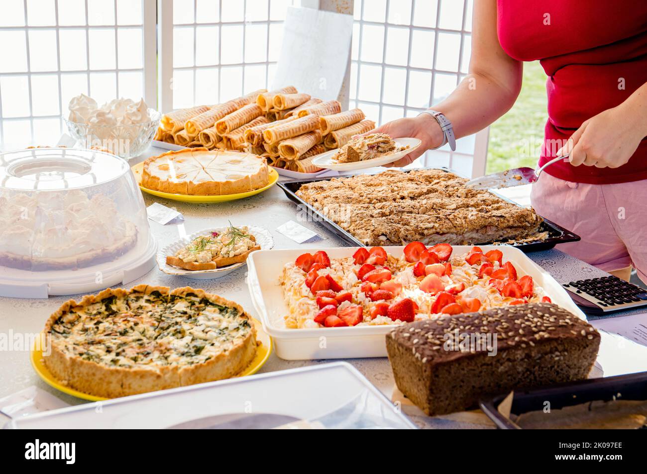 Nahaufnahme der Person, die hausgemachtes Gebäck und Kuchen bei der Tagesveranstaltung im Café zu Hause verkauft. Person hält den Kunden den Kuchen fest und gibt ihm Kuchen. Verschiedene Kuchen. Stockfoto