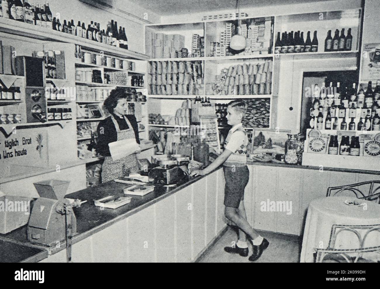 Gut sortiertes Geschäft im ehemaligen Konzentrationslager Dachau. Flüchtlinge im ehemaligen Konzentrationslager Dachau. Dachau war ein am 22. März 1933 eröffnetes Nazi-Konzentrationslager, das zunächst politische Gefangene halten sollte. Es liegt nordwestlich von München im Bundesland Bayern, im Süden Deutschlands. In den Nachkriegsjahren diente die Dachau-Anlage dazu, SS-Soldaten in Erwartung des Prozesses zu halten. Nach 1948 hielt es ethnische Deutsche fest, die aus Osteuropa ausgewiesen worden waren und auf eine Umsiedlung warteten, und wurde während der Besatzung auch eine Zeit lang als Militärstützpunkt der Vereinigten Staaten genutzt. Es war fina Stockfoto