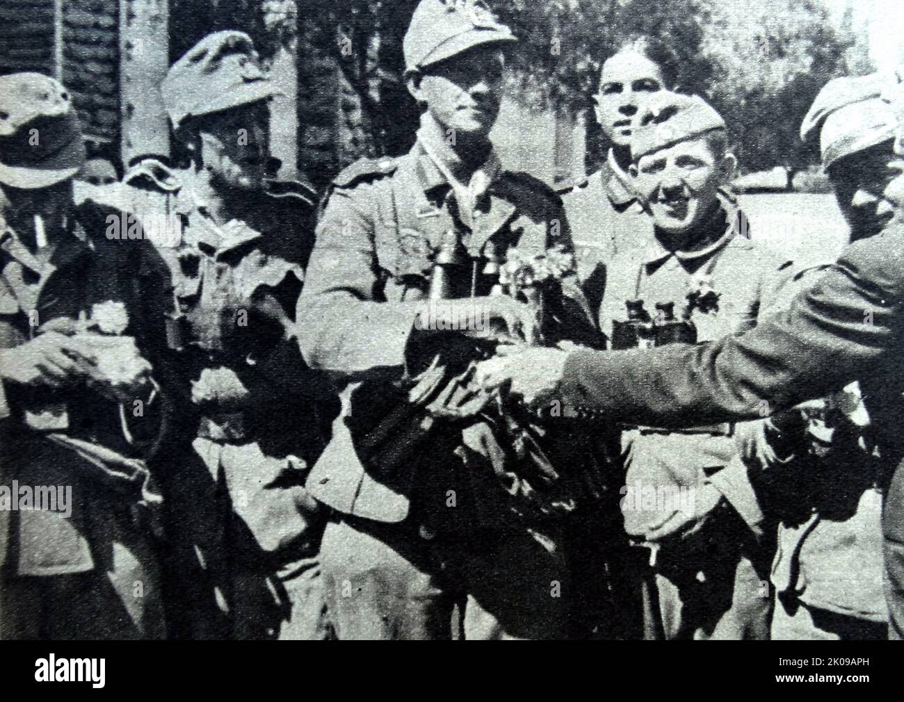 Bei der Einreise nach Athen Zigaretten und Blumen an Nazi-Truppen verteilen, fotografiert von Heinrich Hoffmann. Heinrich Hoffmann (12. September 1885 - 15. Dezember 1957) war Adolf Hitlers offizieller Fotograf und ein Nazi-Politiker und Verleger, der Mitglied des intimen Hitlerkreises war. Stockfoto