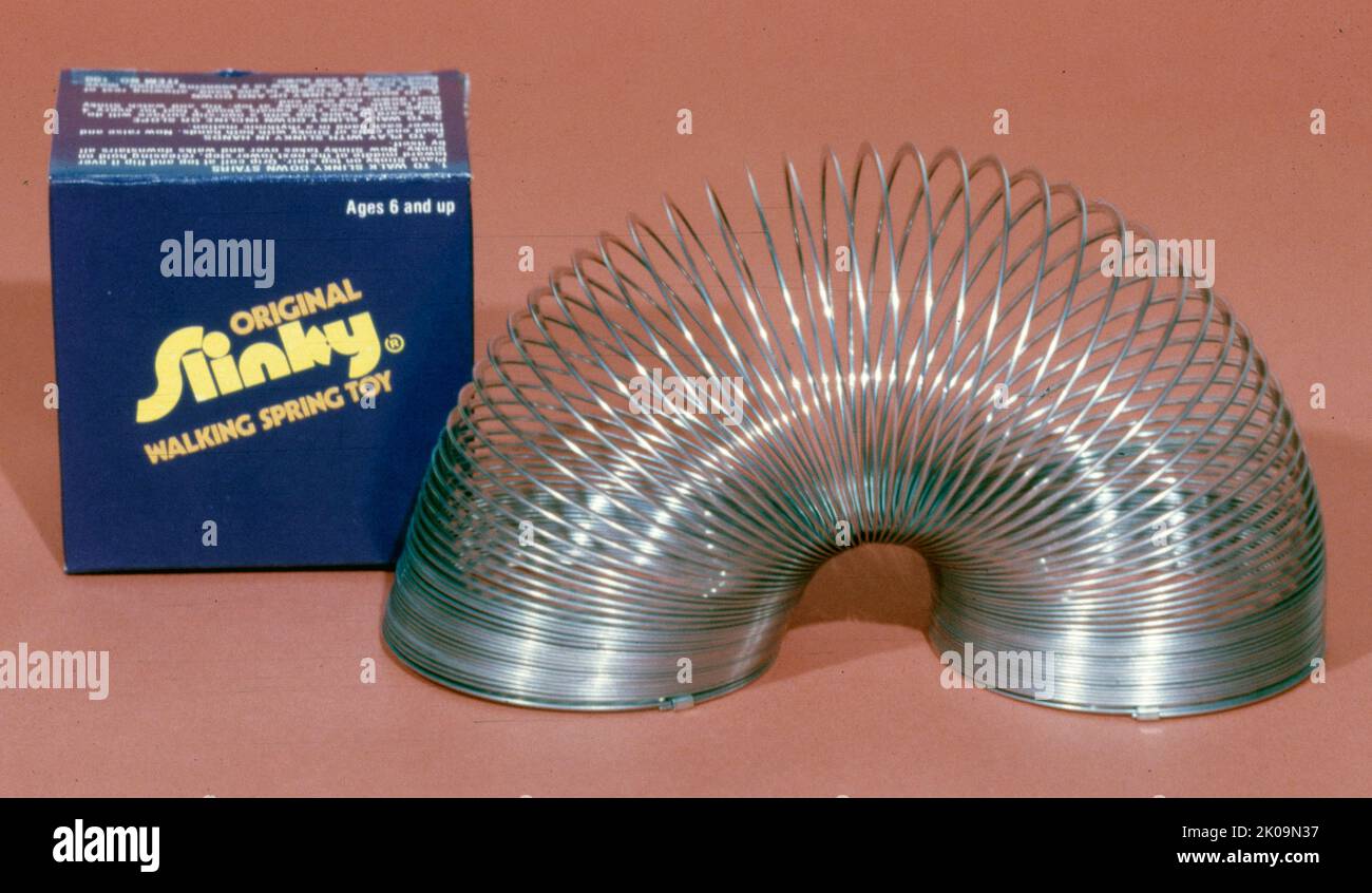 Ein Slinky ist ein vorkomprimiertes spiralförmige Federspielzeug, das von Richard James Anfang 1940s erfunden wurde. Er kann eine Reihe von Tricks ausführen, einschließlich einer Reihe von Schritten, die sich mit Hilfe der Schwerkraft und seines eigenen Impulses ausdehnen und neu Formen, durchfahren, oder nach dem Fallenlassen für eine gewisse Zeit zu schweben scheinen. Stockfoto