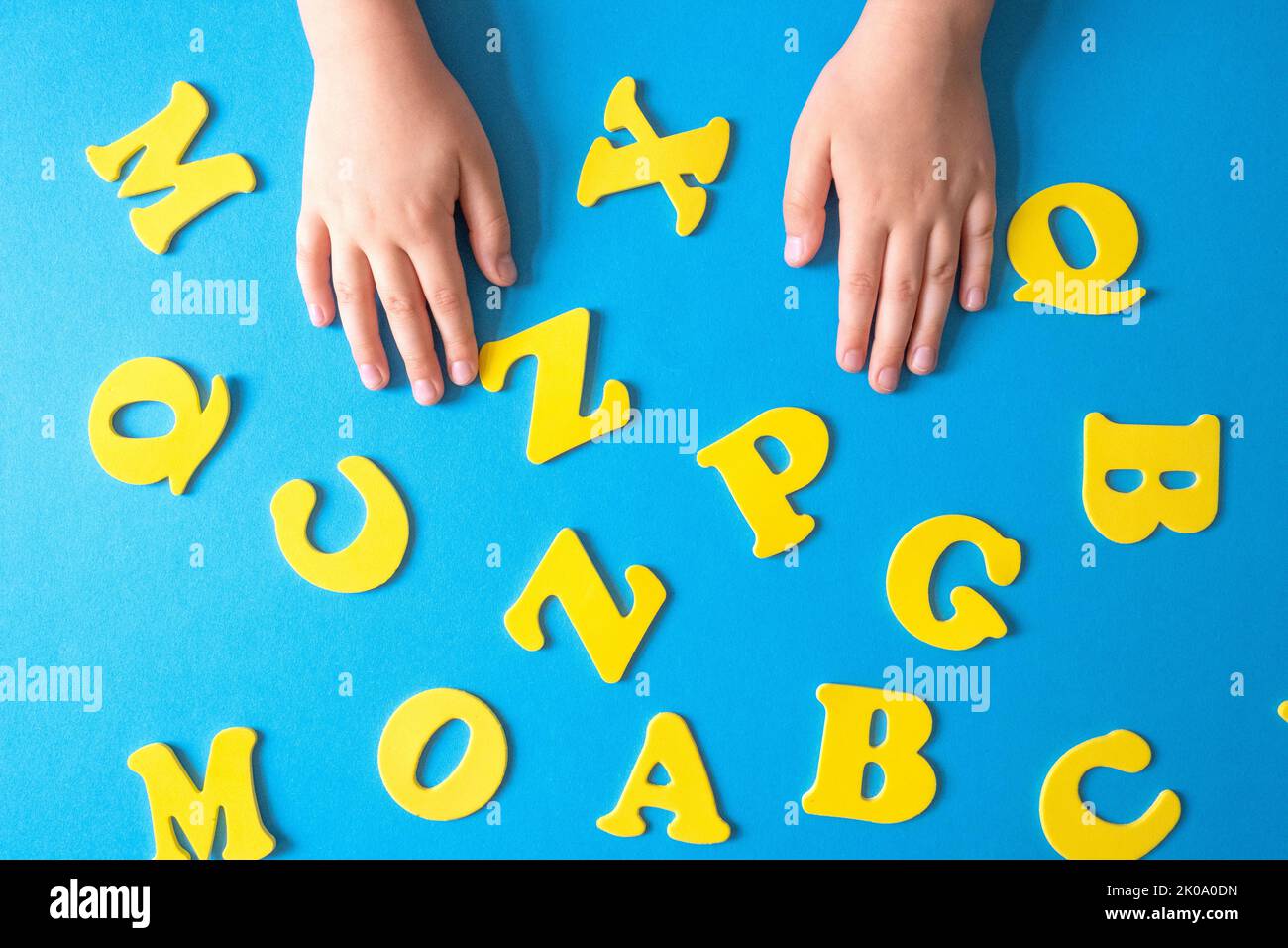 Gelbe Buchstaben auf blauem Hintergrund. Kinderhände lizenzfreie Bilder Stockfoto
