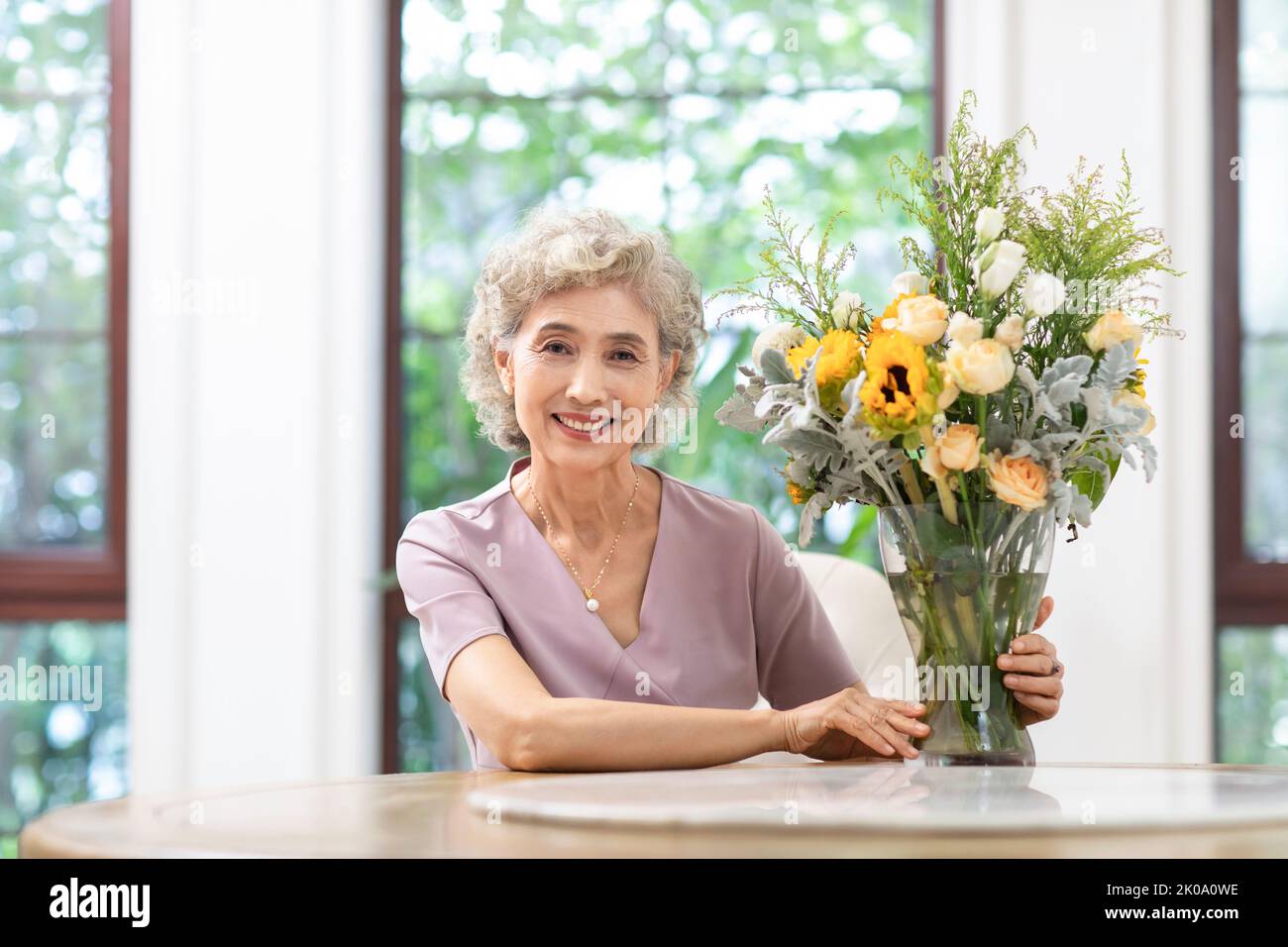 Glückliche ältere chinesische Frau, die zu Hause Blumen arrangiert Stockfoto
