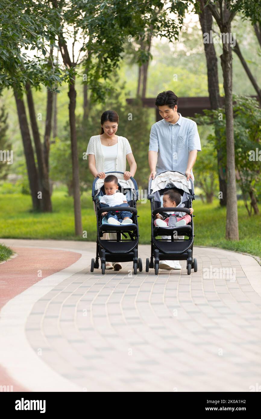 Junge chinesische Eltern mit Zwillingsbabys im Kinderwagen Stockfoto