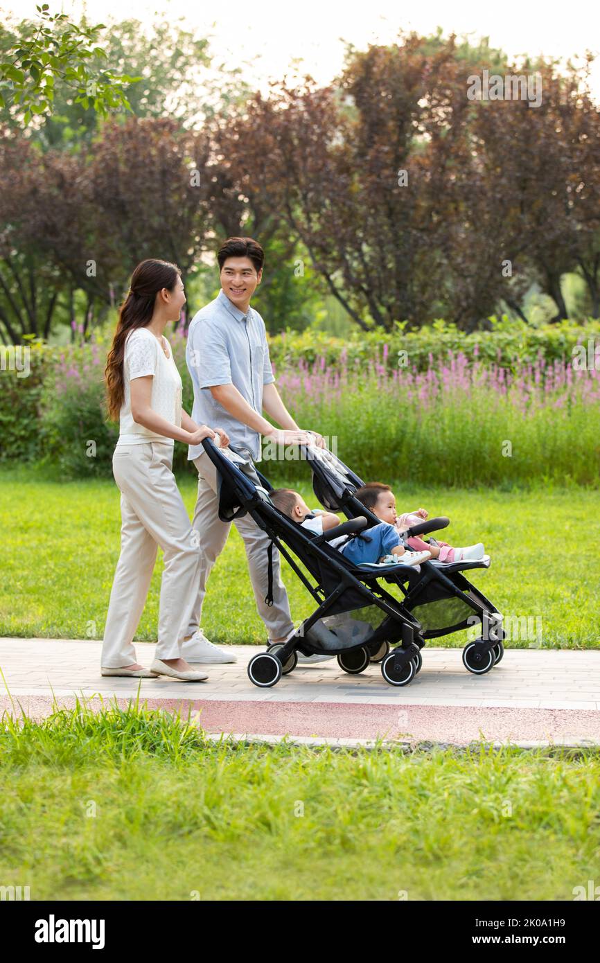 Junge chinesische Eltern mit Zwillingsbabys im Kinderwagen Stockfoto