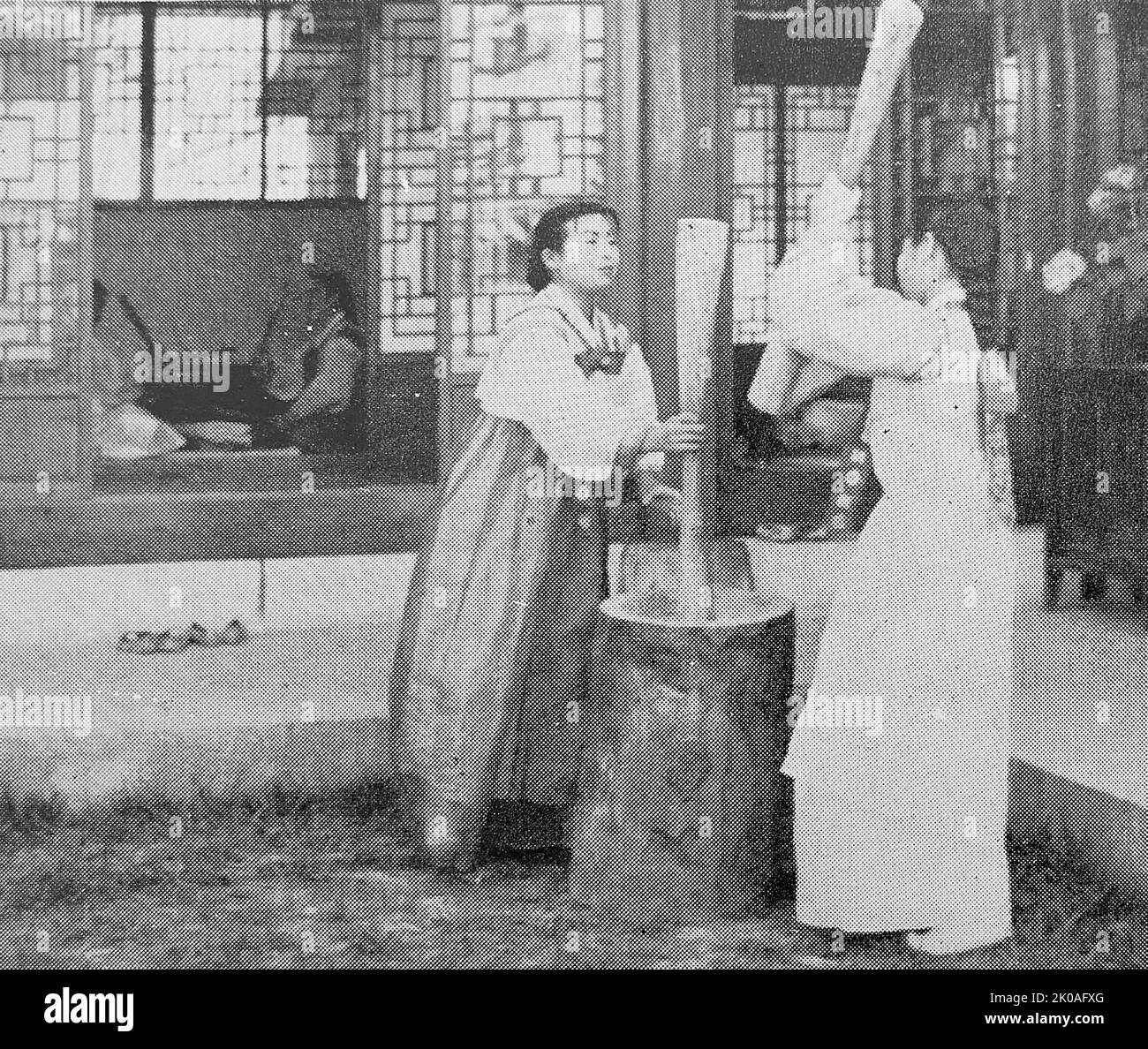 Frauen, die Reis stampfen, Korea in Dörfern wurde eine solche hölzerne Handmühle immer noch verwendet, um Reiskuchen und andere Lebensmittel zu machen. Stockfoto