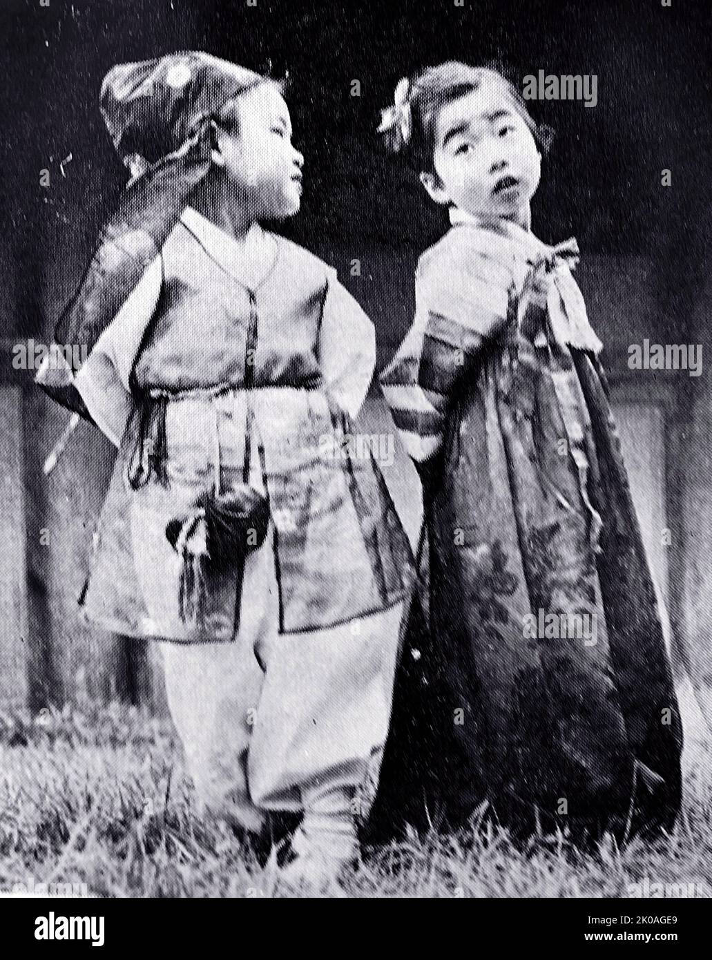 Das Mädchen trägt ein Jeogo-ri (oben) und ein Kleid (Chima). Der Junge trägt eine Mütze namens „Pokkon“, vor ihm baumelt eine Handtasche. Stockfoto