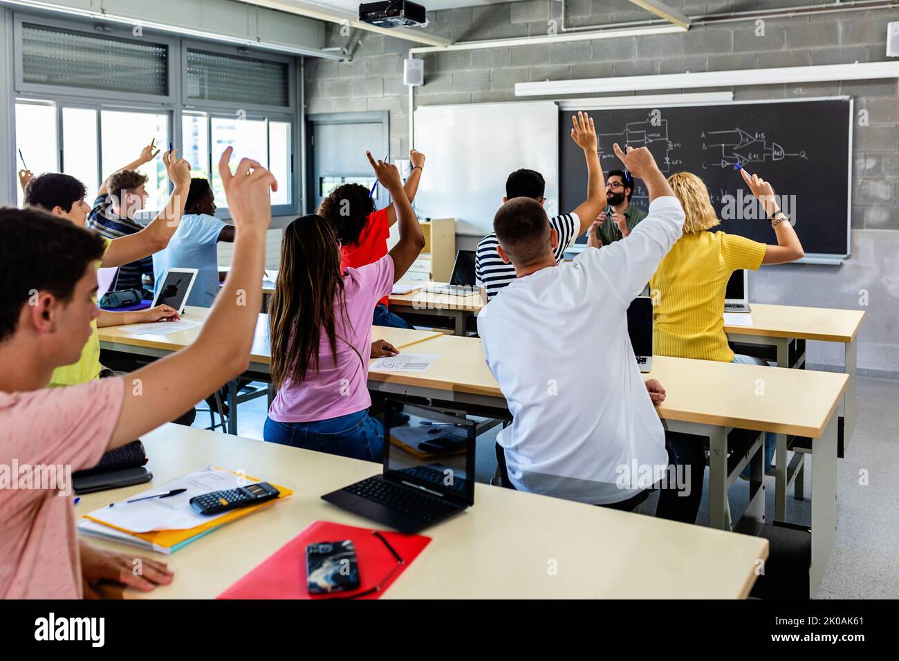 Gruppe von Schülern, die im Klassenzimmer die Hände heben Stockfoto