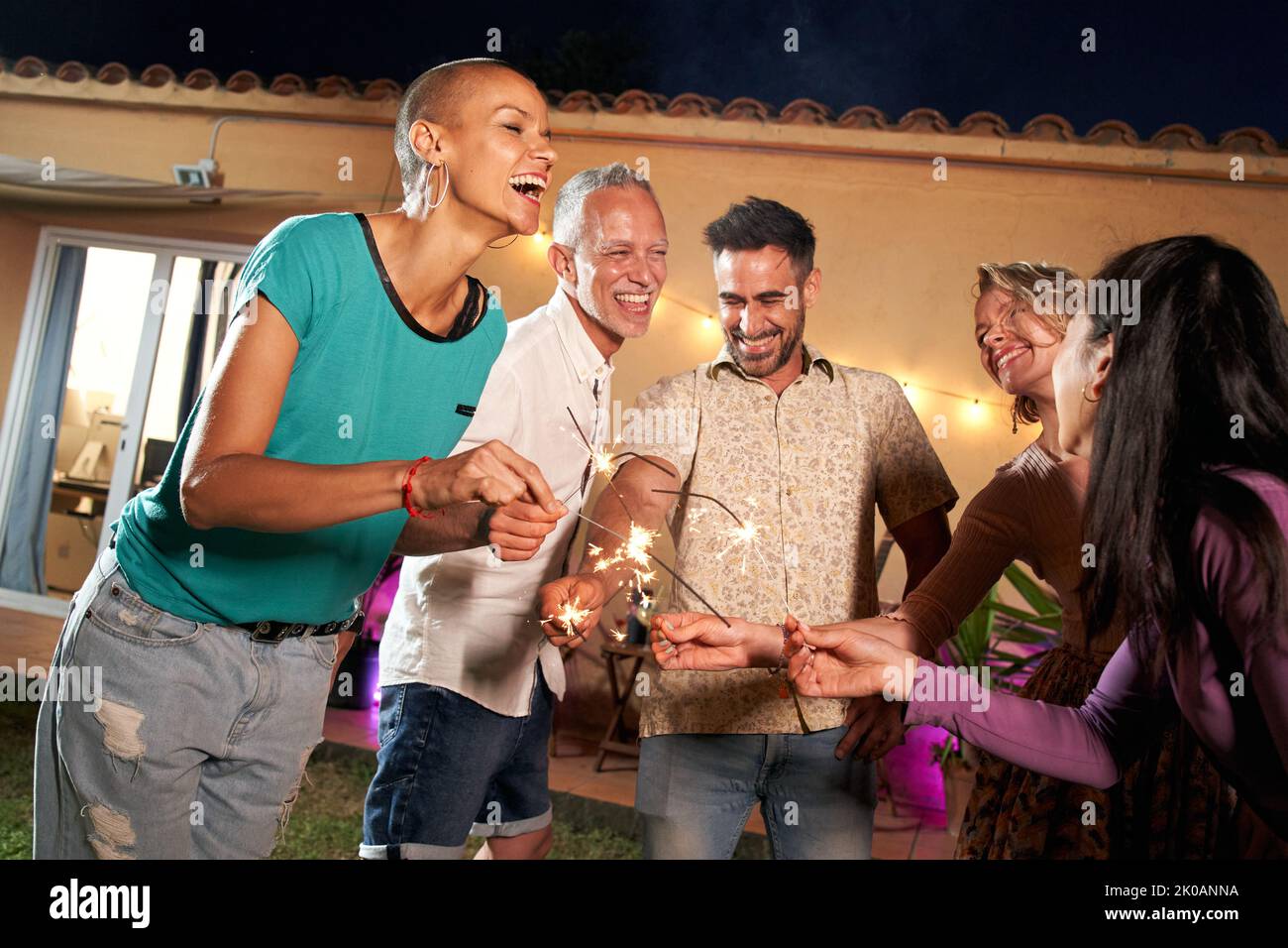 Eine Gruppe reifer Freunde feiert mit Funke auf einer privaten Party im Hinterhof oder in einem Club. Fröhliche und fröhliche Menschen feiern im Freien Stockfoto