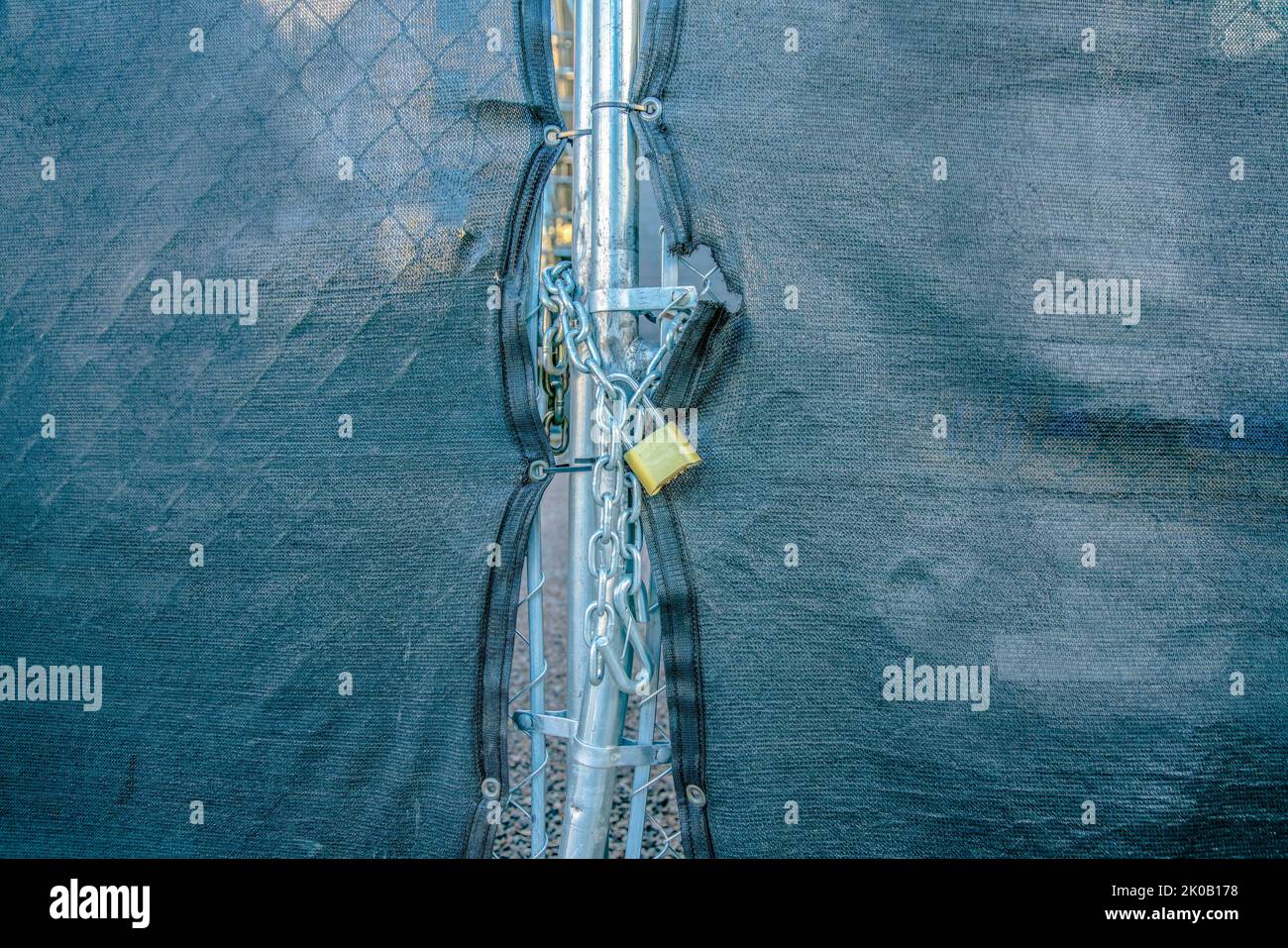 Vorhängeschloss mit Kettenglied auf einem Gitterzaun mit Abdeckung in der Innenstadt von Tucson, Arizona. Tor mit schwarzer Abdeckung und Vorhängeschloss mit Kettenglied in der Mitte. Stockfoto