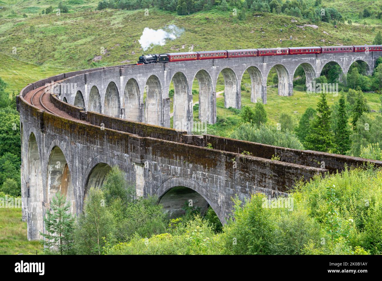 Die Jacobite Dampflokomotive, Touristenzug, beginnt, die ikonische Viaduktbrücke zu überqueren, auf der West Highland Line, beliebtes Touristenziel Wahrzeichen, durch Stockfoto