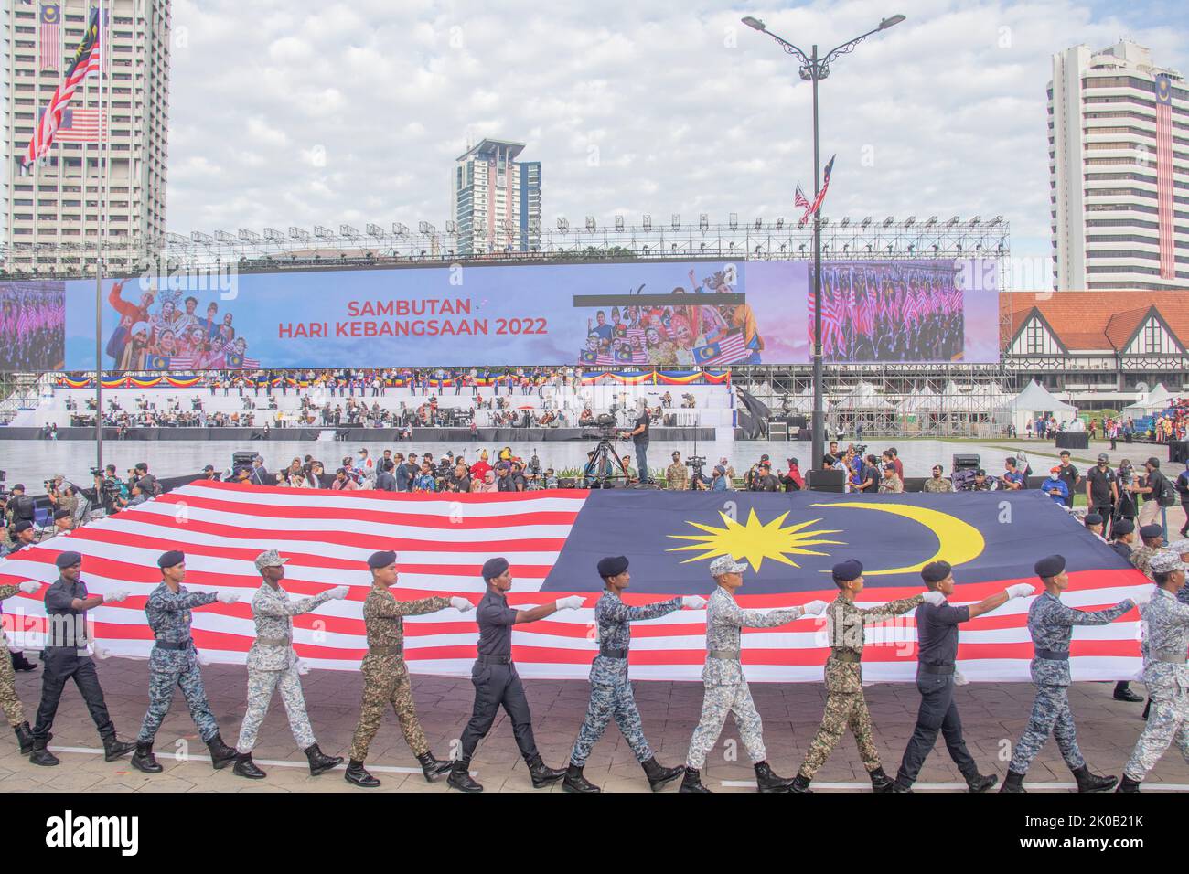 Junge Kadetten der malaysischen Streitkräfte von Armee, Marine, Seeschifffahrt, Luftwaffe und Polizei marschieren mit der riesigen Malaysia-Flagge Stockfoto