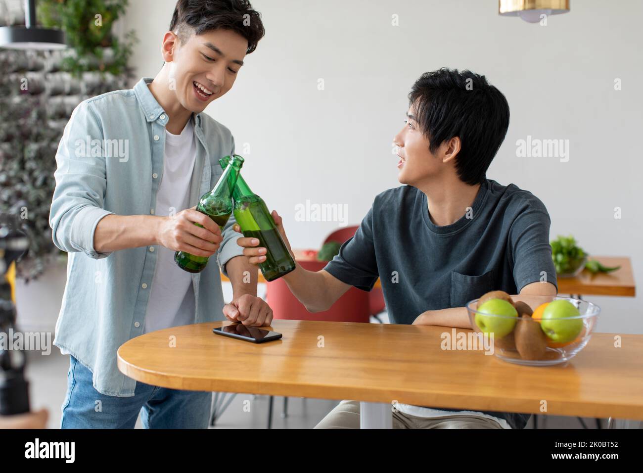 Glückliche junge chinesische Freunde trinken Bier Stockfoto