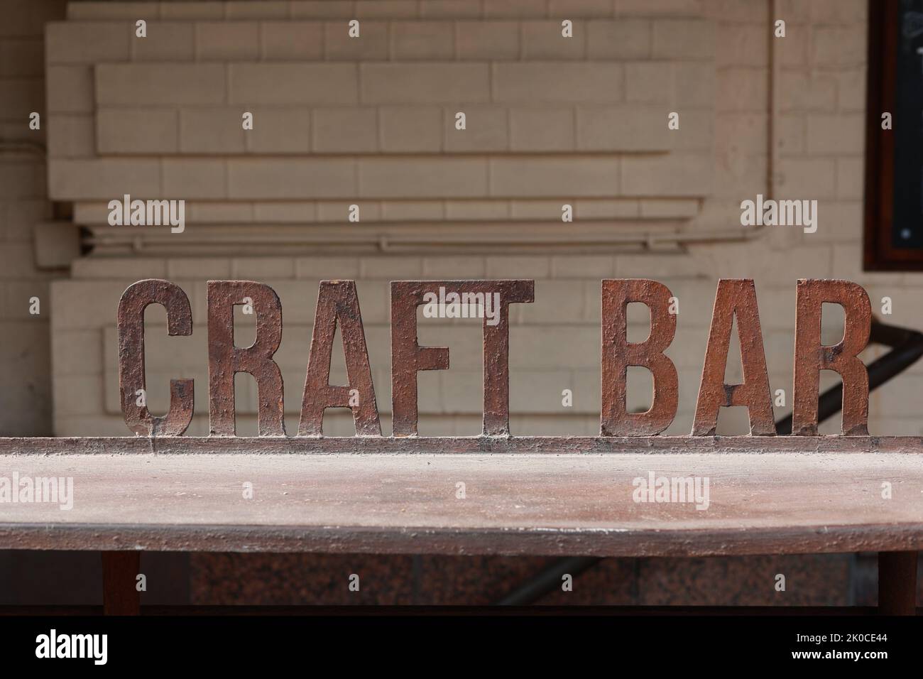 Iron signboard Craft Bar und Barcounter. Eintritt zu einem Craft Beer Establishment. Verwackelte Backsteinmauer im Hintergrund. Stockfoto
