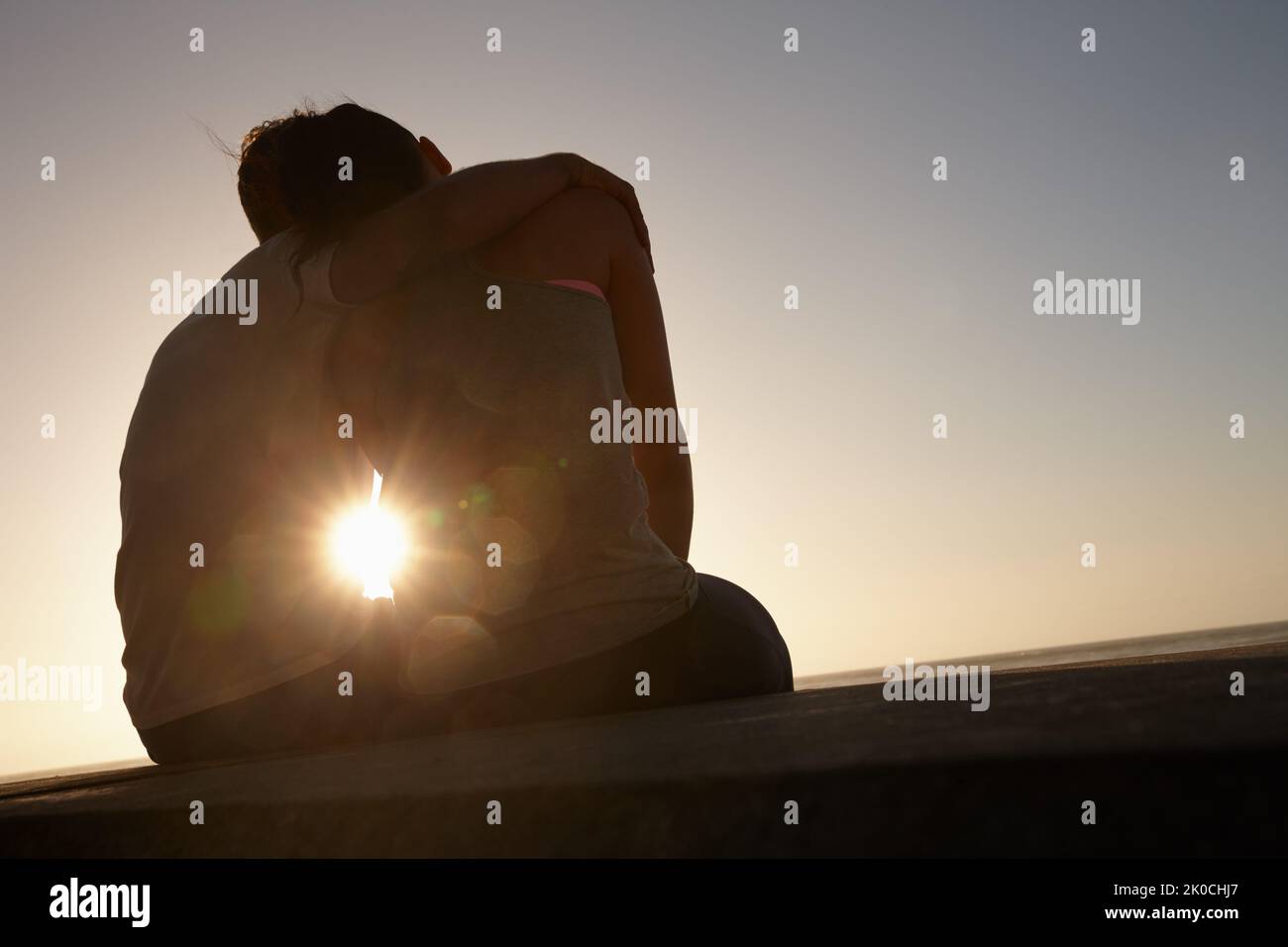 Echte Romantik bei Sonnenuntergang. Silhouette eines Paares, das draußen nebeneinander sitzt. Stockfoto