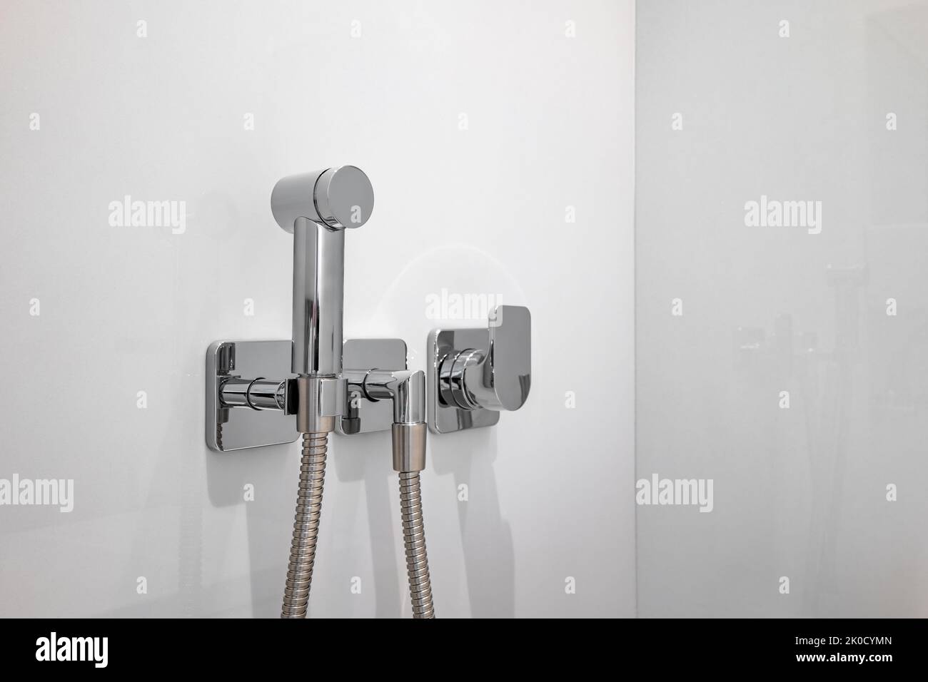 Chrom-Bidet-Dusche mit weißen Fliesen in einer Toilette. Saubere und neue Sprühdusche. Stockfoto